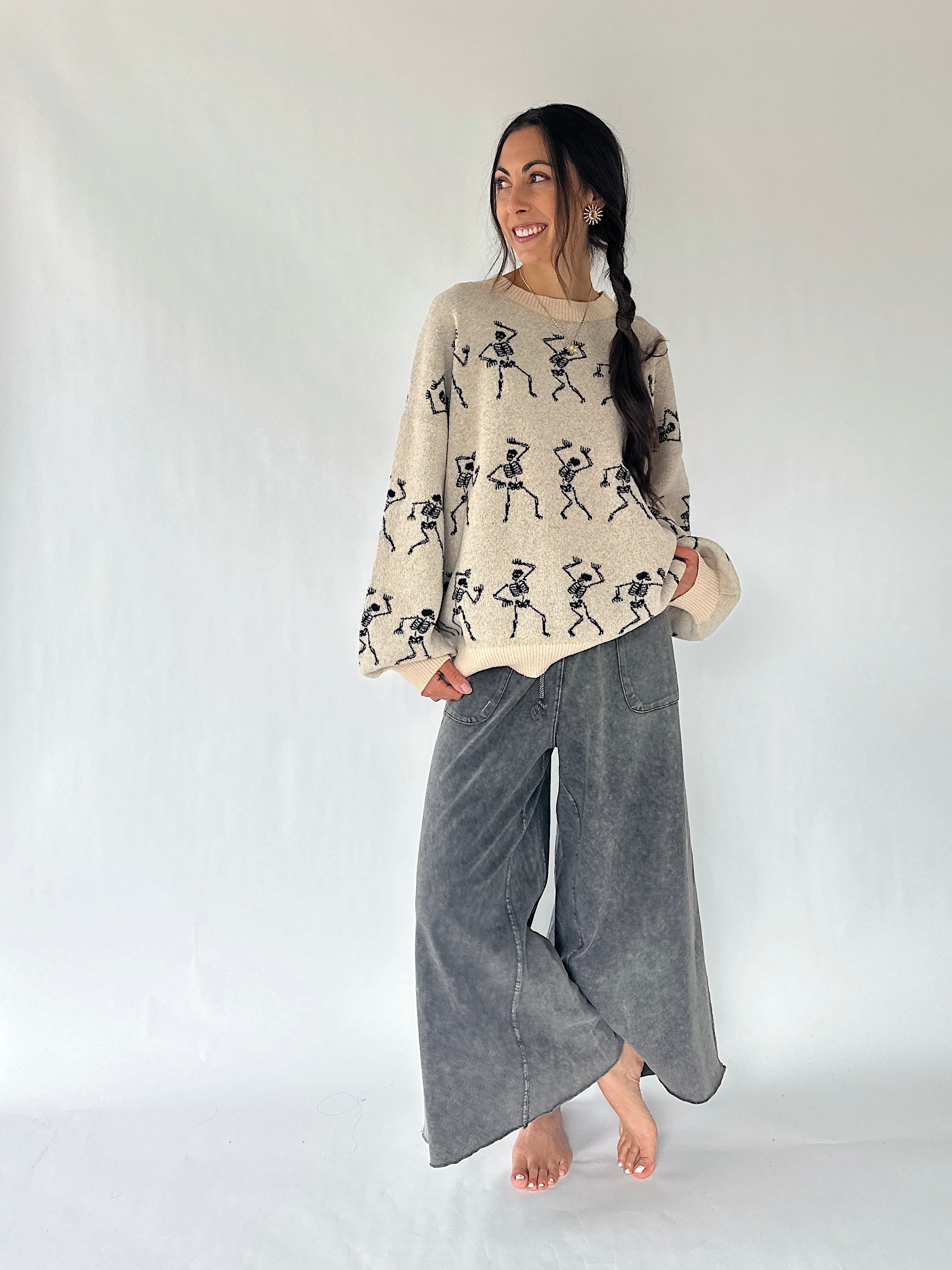 woman wearing dancing skeleton sweater with grey wide leg sweatpants