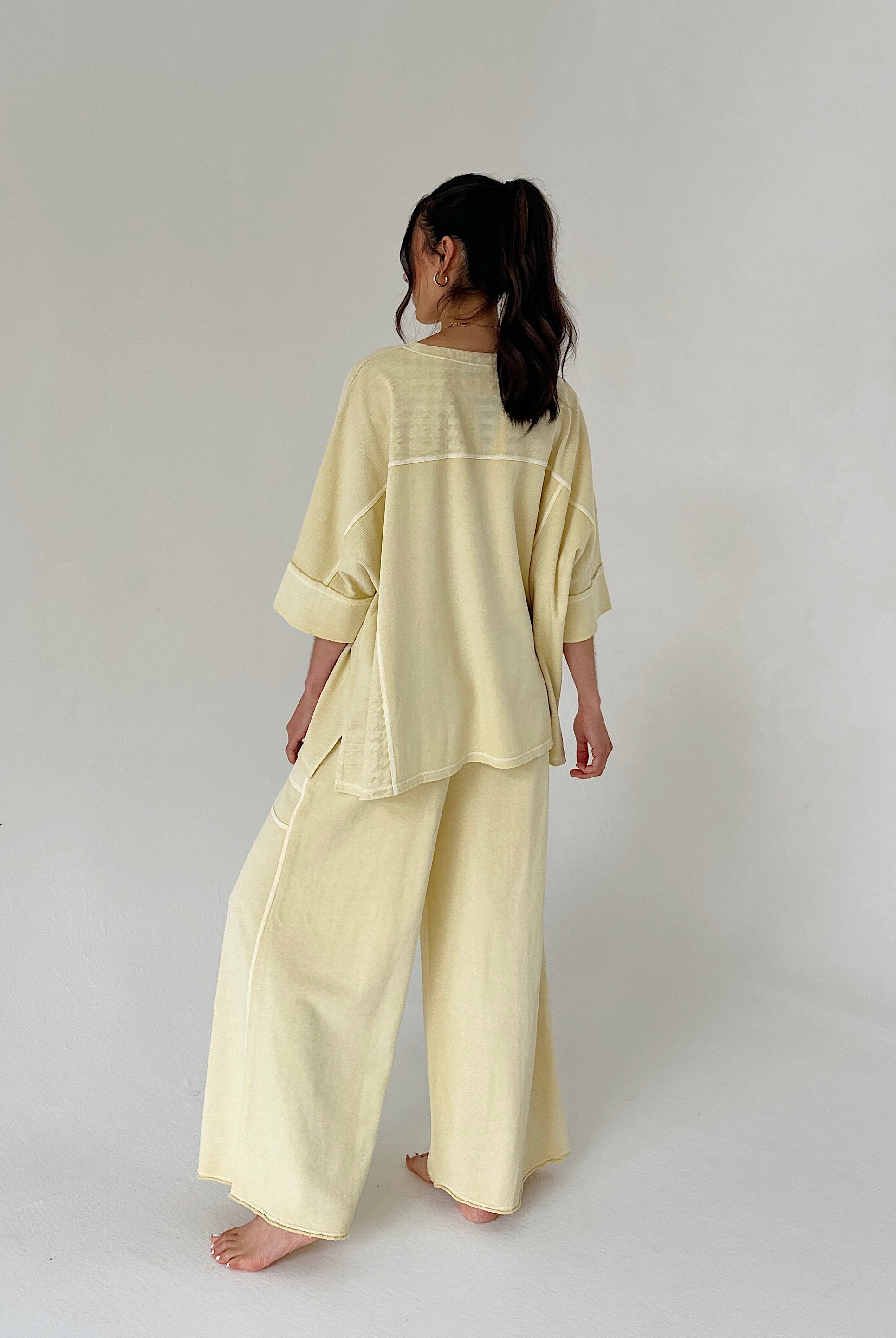 Person wearing a light yellow outfit on a plain background from back