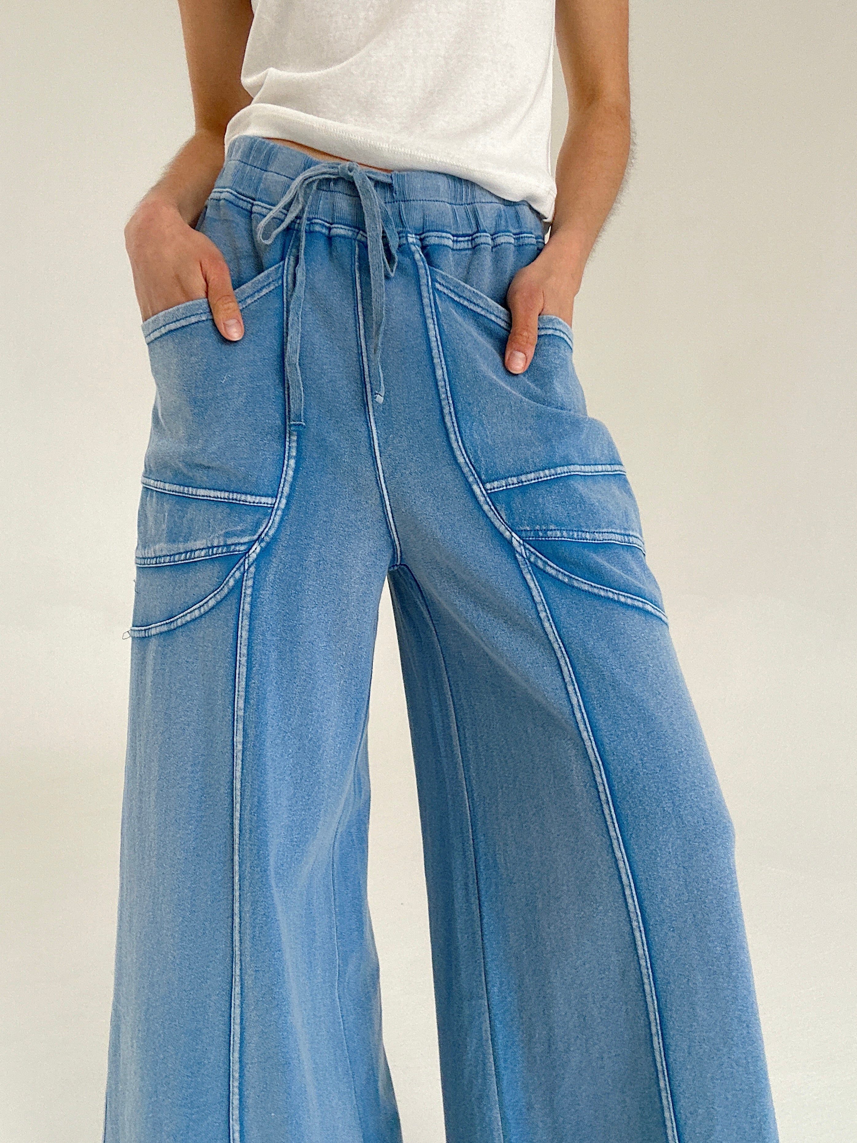 Person wearing blue wide-leg pants with a drawstring waist and pockets on a white background