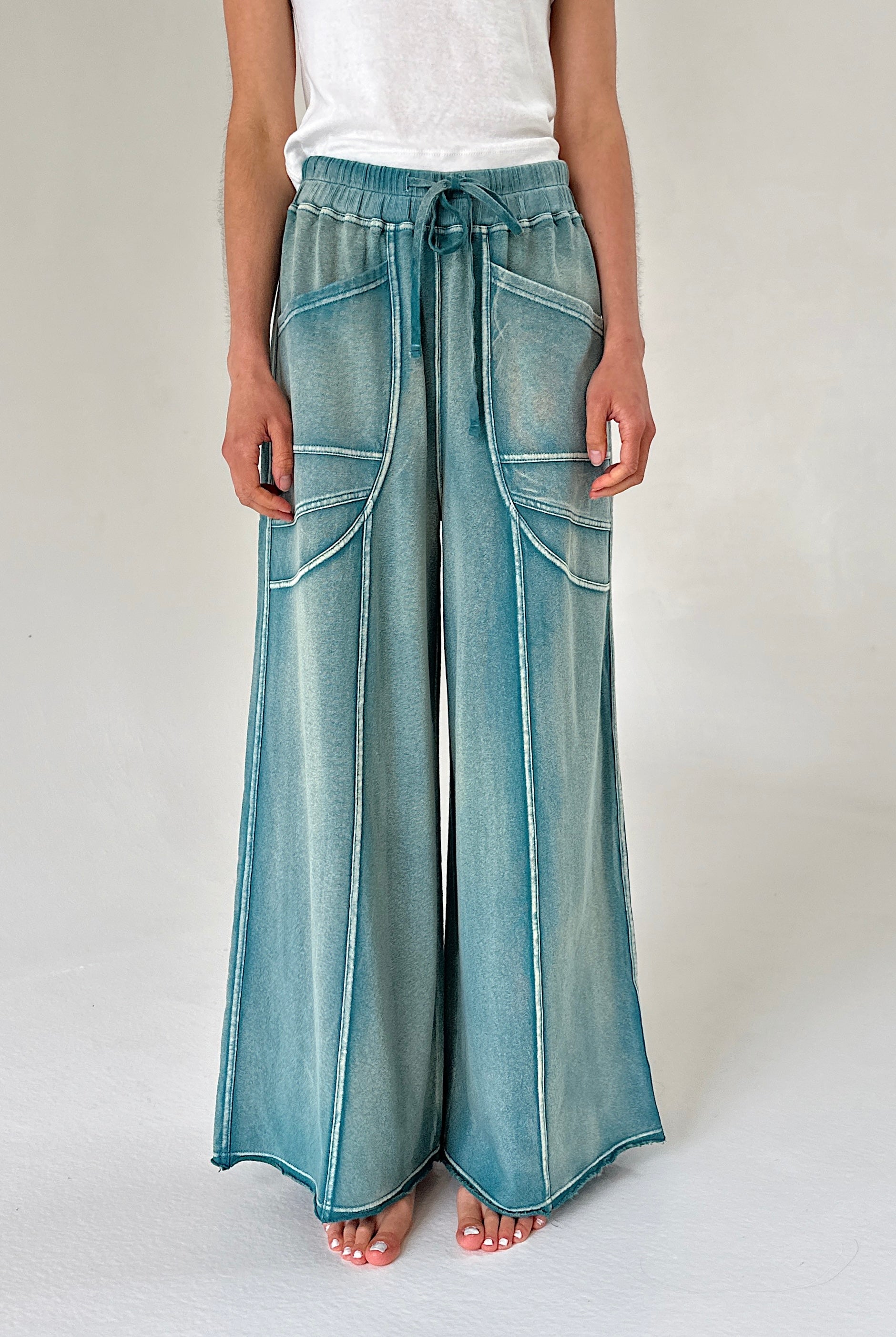 Wide-leg pants in washed teal worn by a person on a plain background