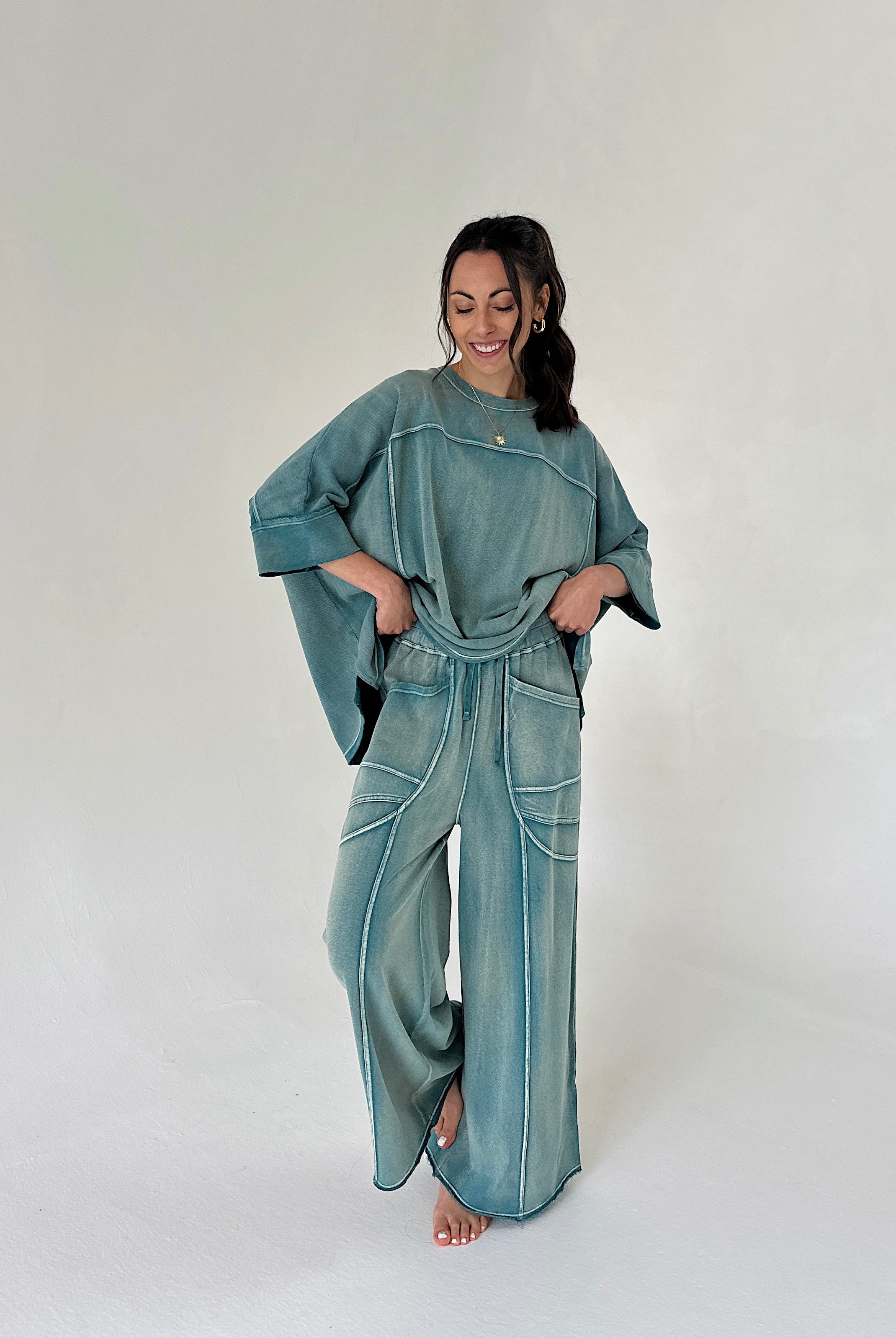 Woman wearing a teal outfit with wide-leg pants on a white background