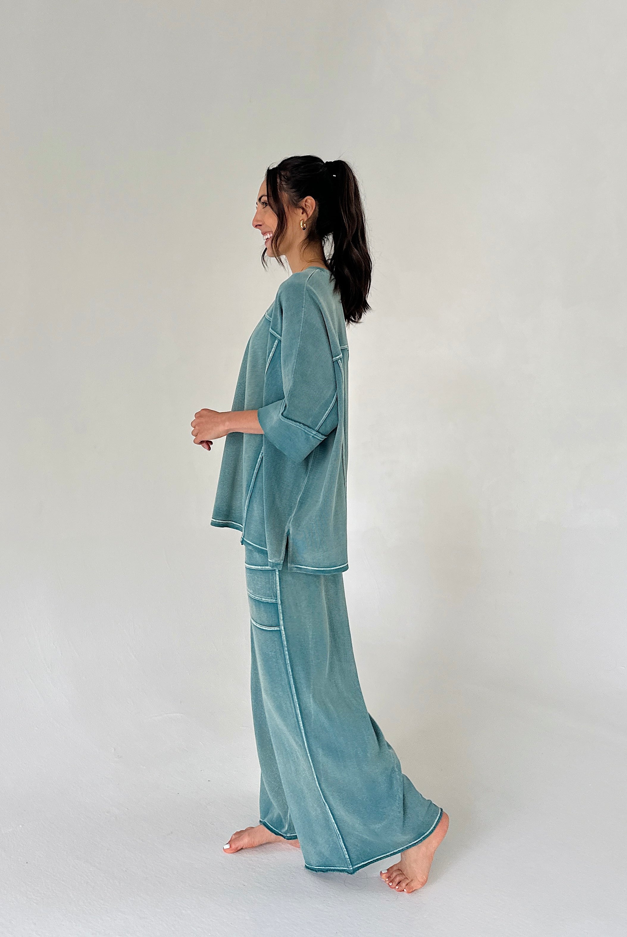 Woman wearing a teal loungewear set on a plain background