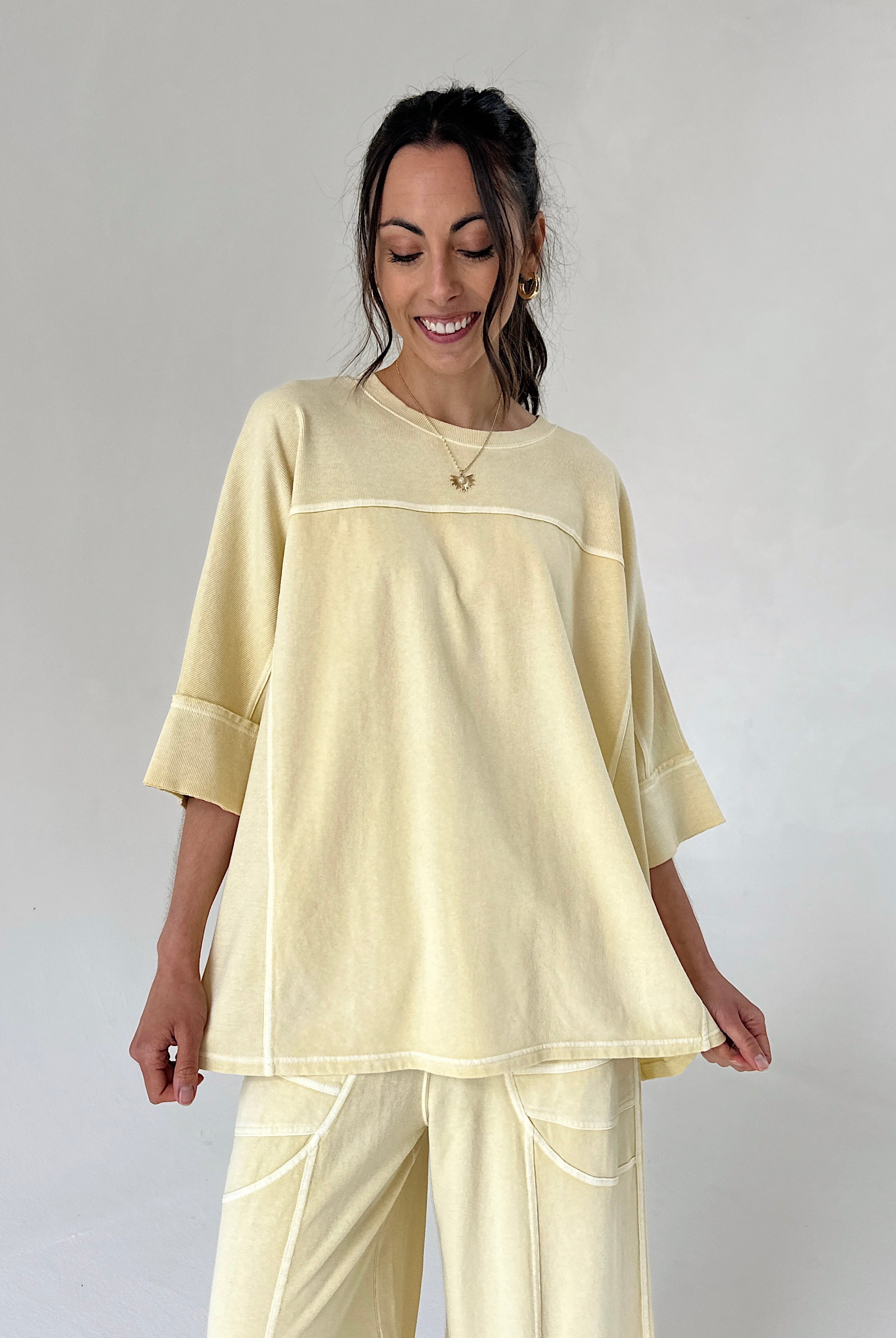 Woman wearing a light yellow outfit against a plain background