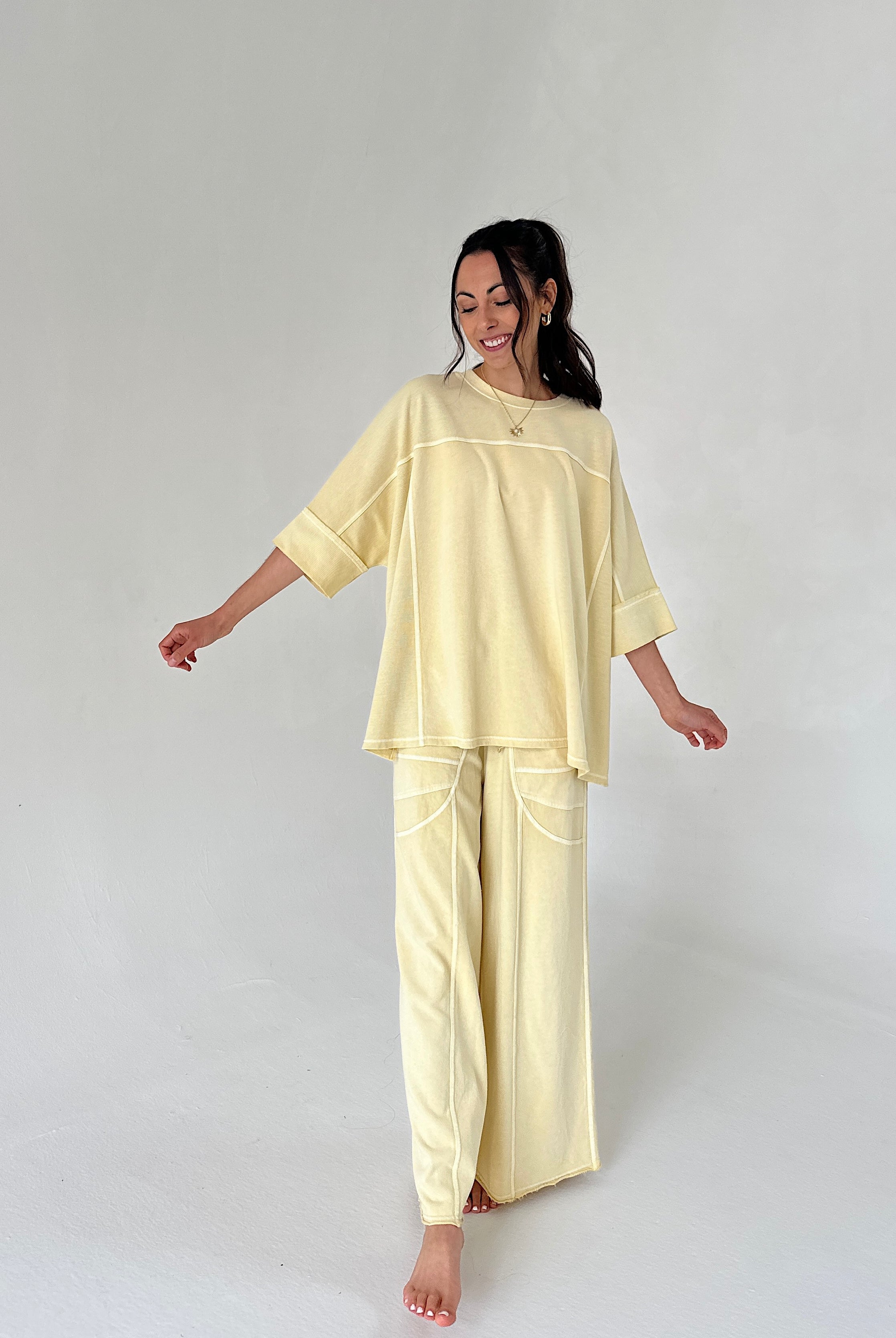 Woman wearing a light yellow matching lounge set on a white background