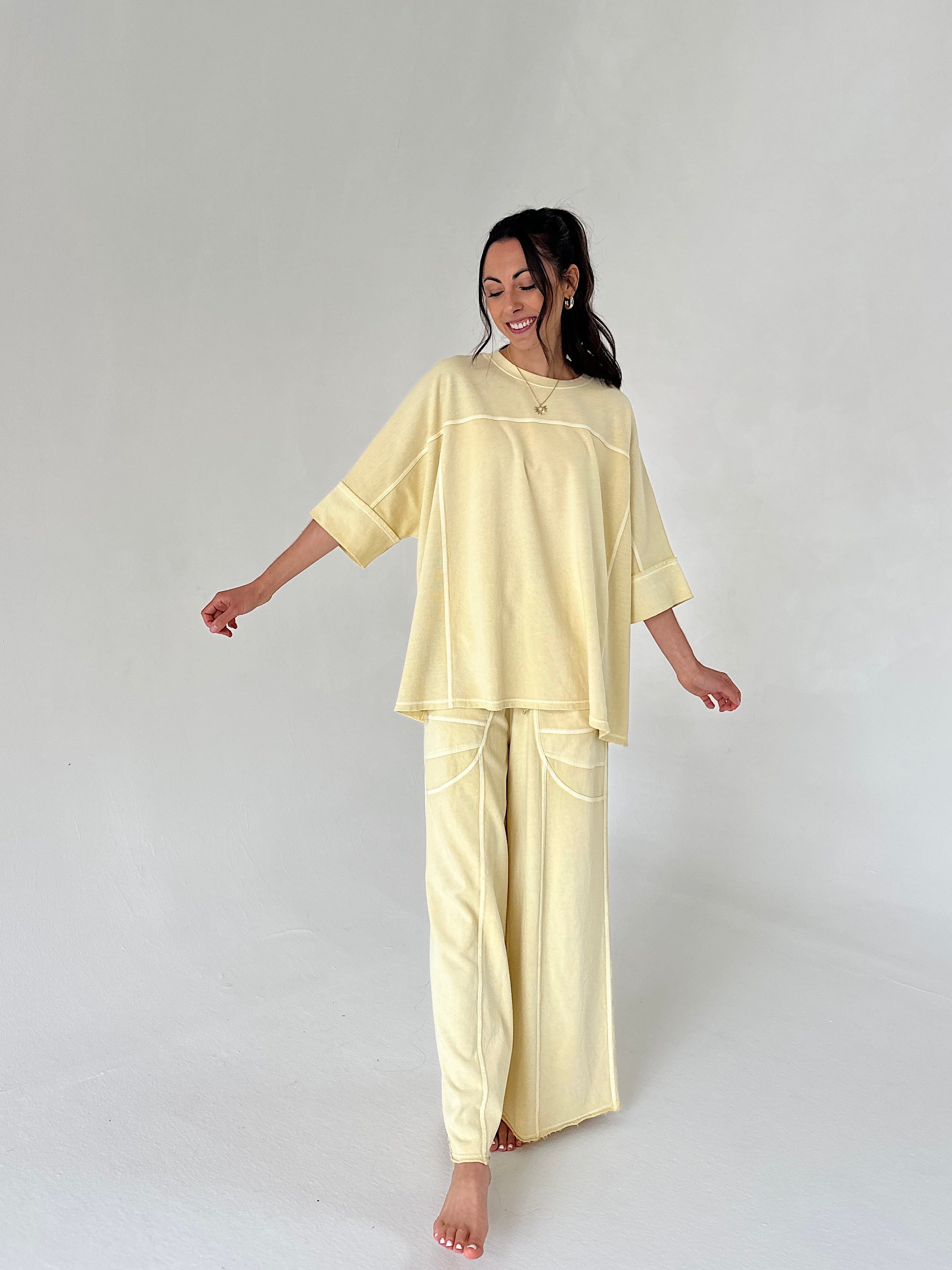 Woman wearing a light yellow matching lounge set on a white background