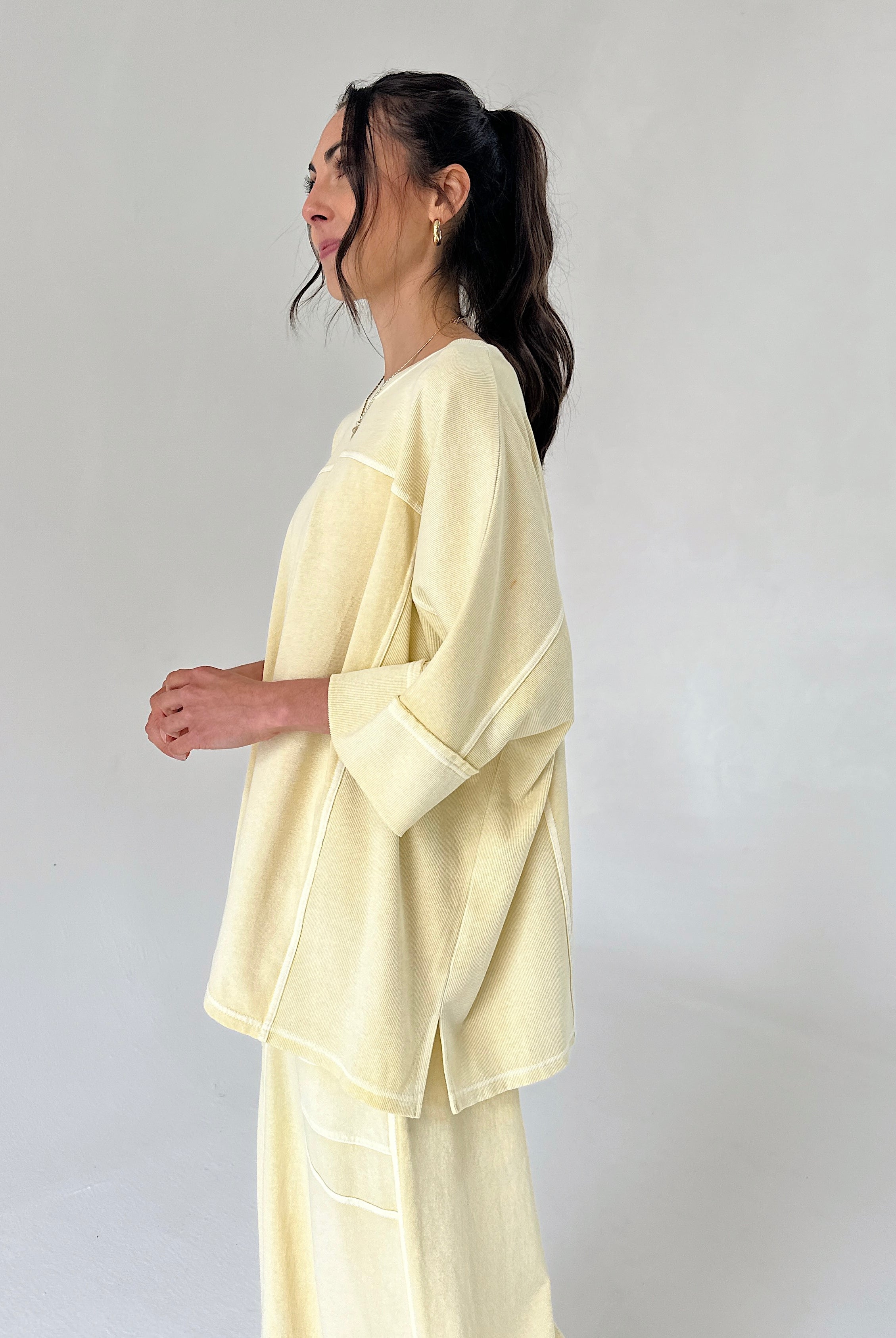 Woman wearing a light yellow outfit against a plain background