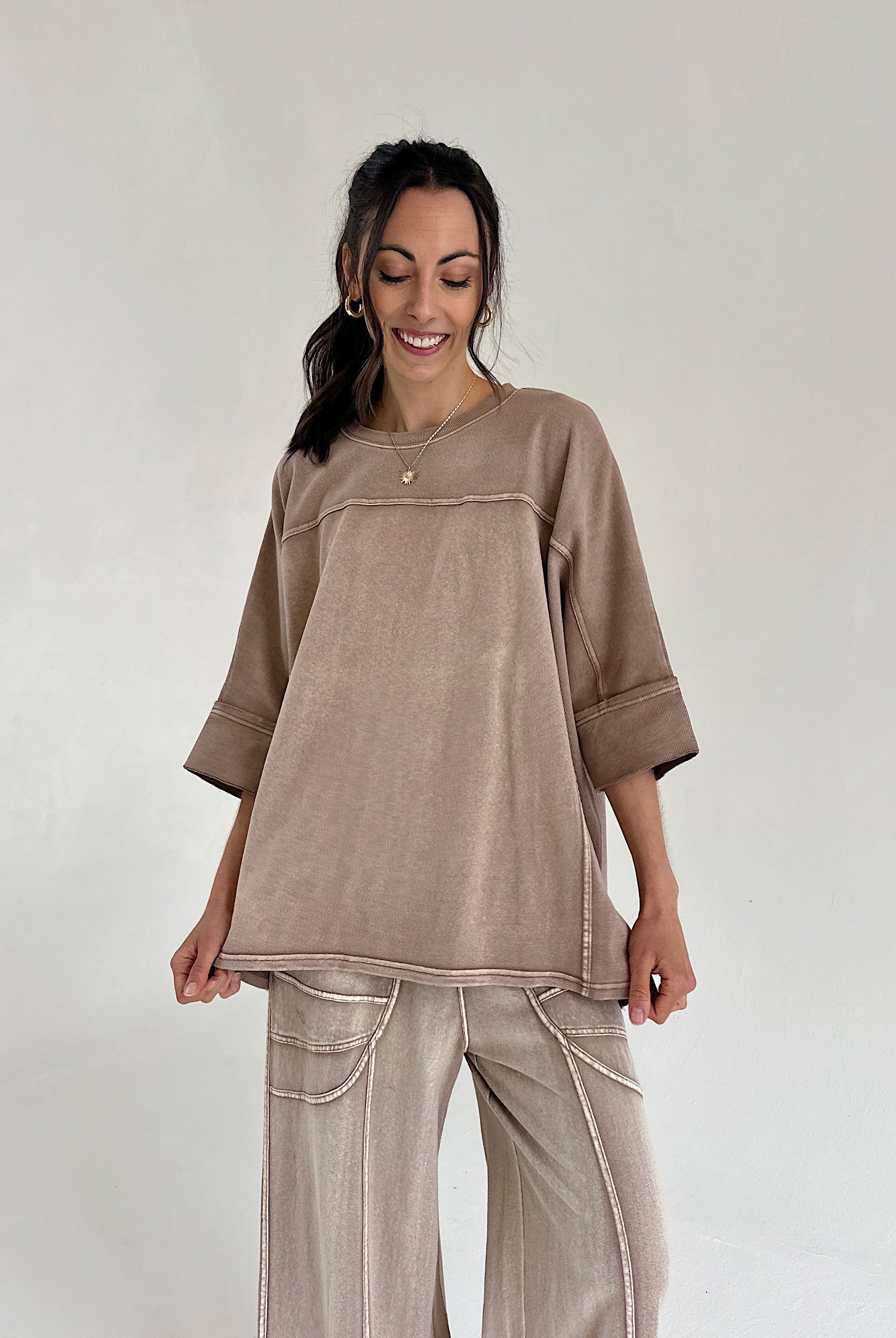 Woman wearing a brown top and pants set on a plain background
