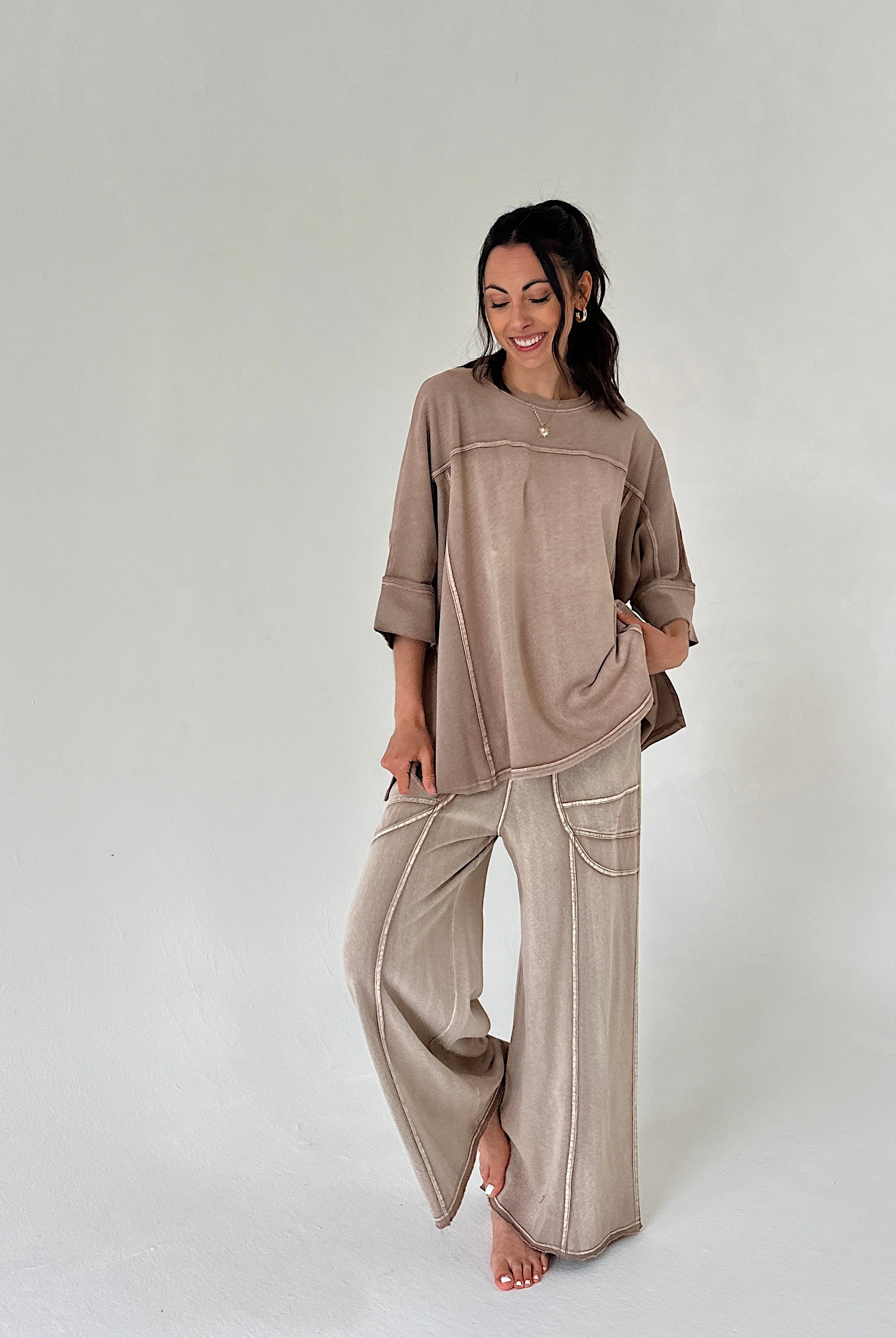 Woman wearing a beige outfit with wide-leg pants on a white background