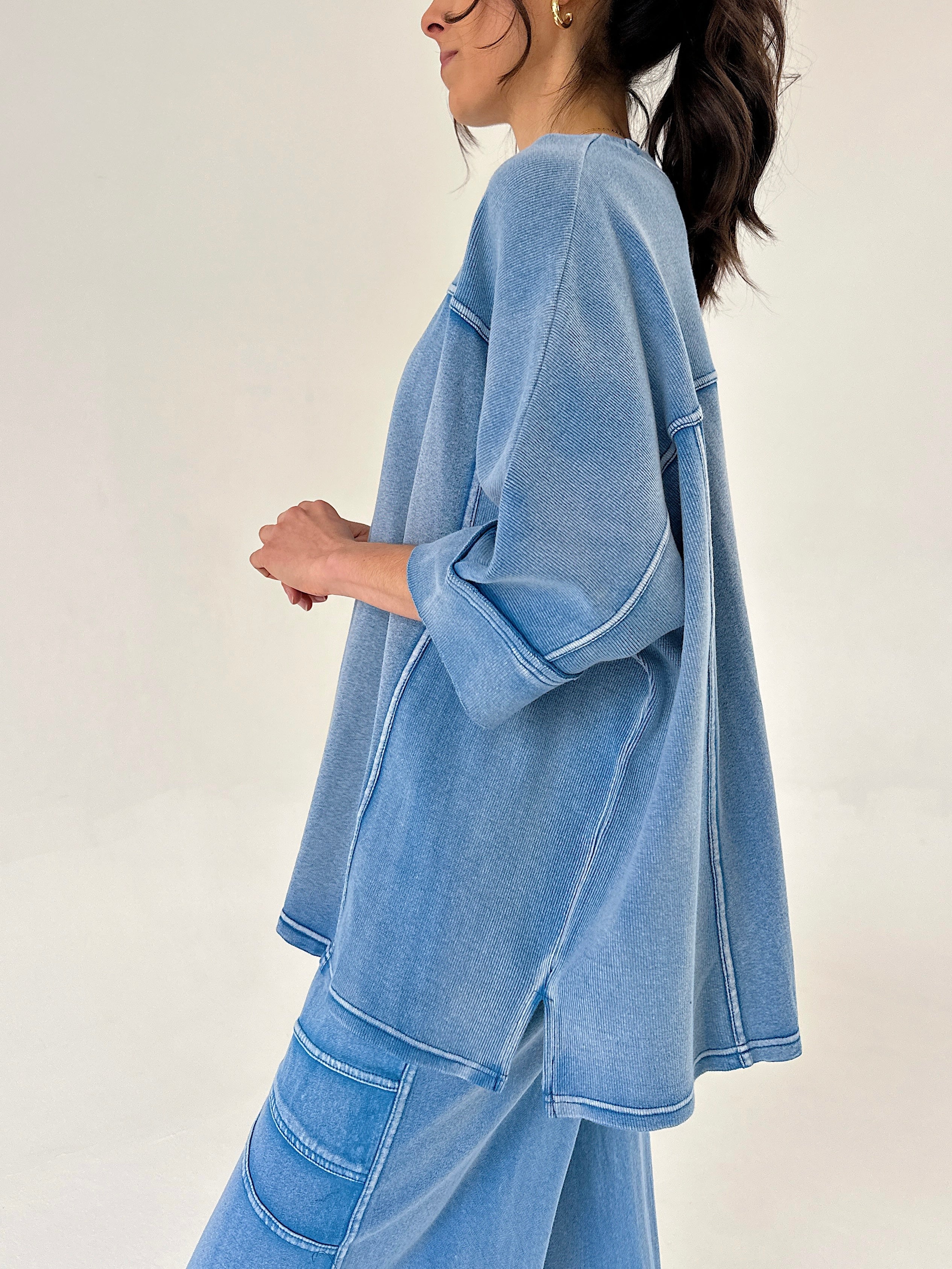 Person wearing a blue matching lounge outfit on a plain background showing top side