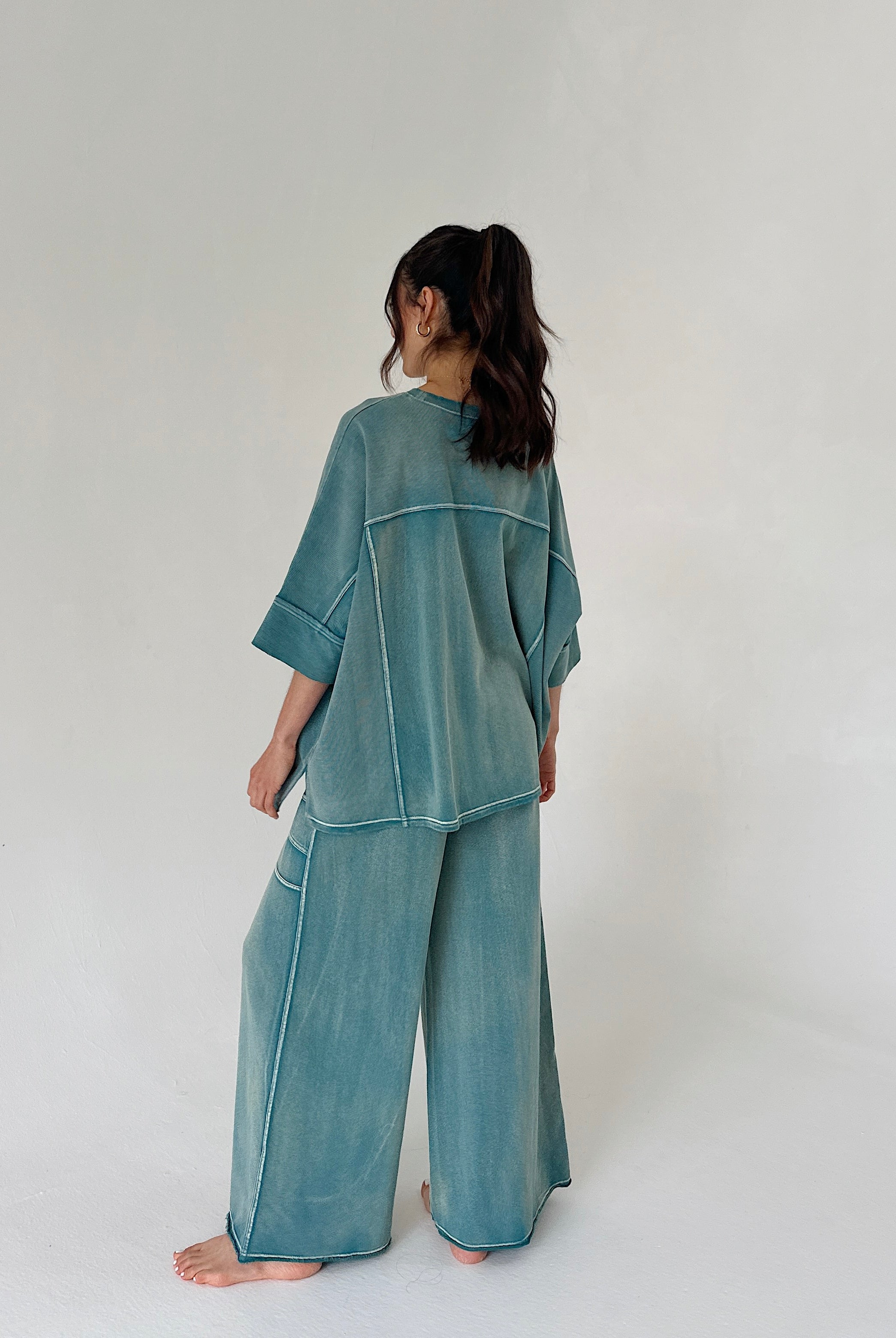 Person wearing a teal outfit on a white background from back