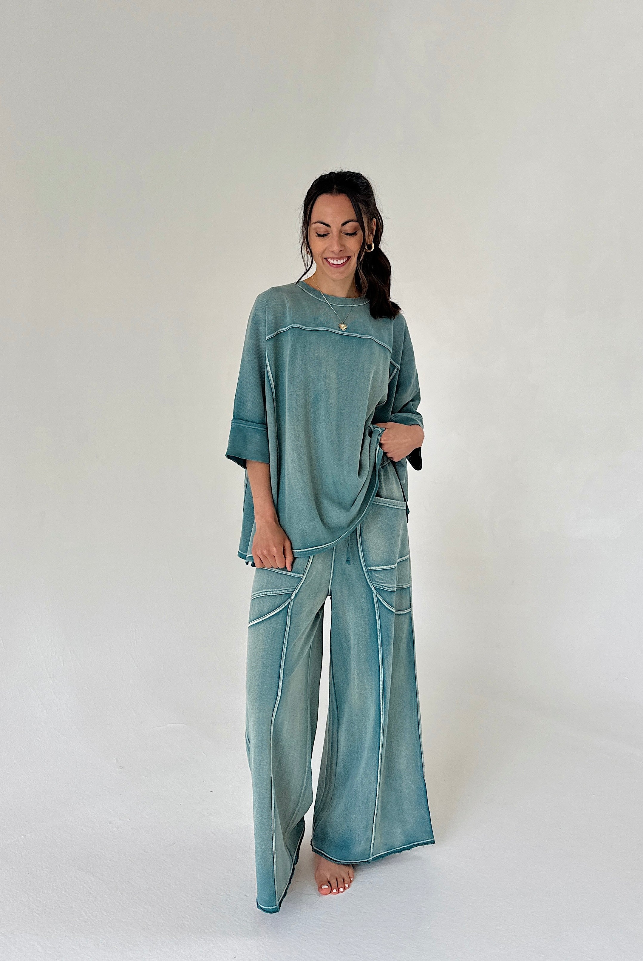 Woman wearing a teal outfit with wide-leg pants on a white background