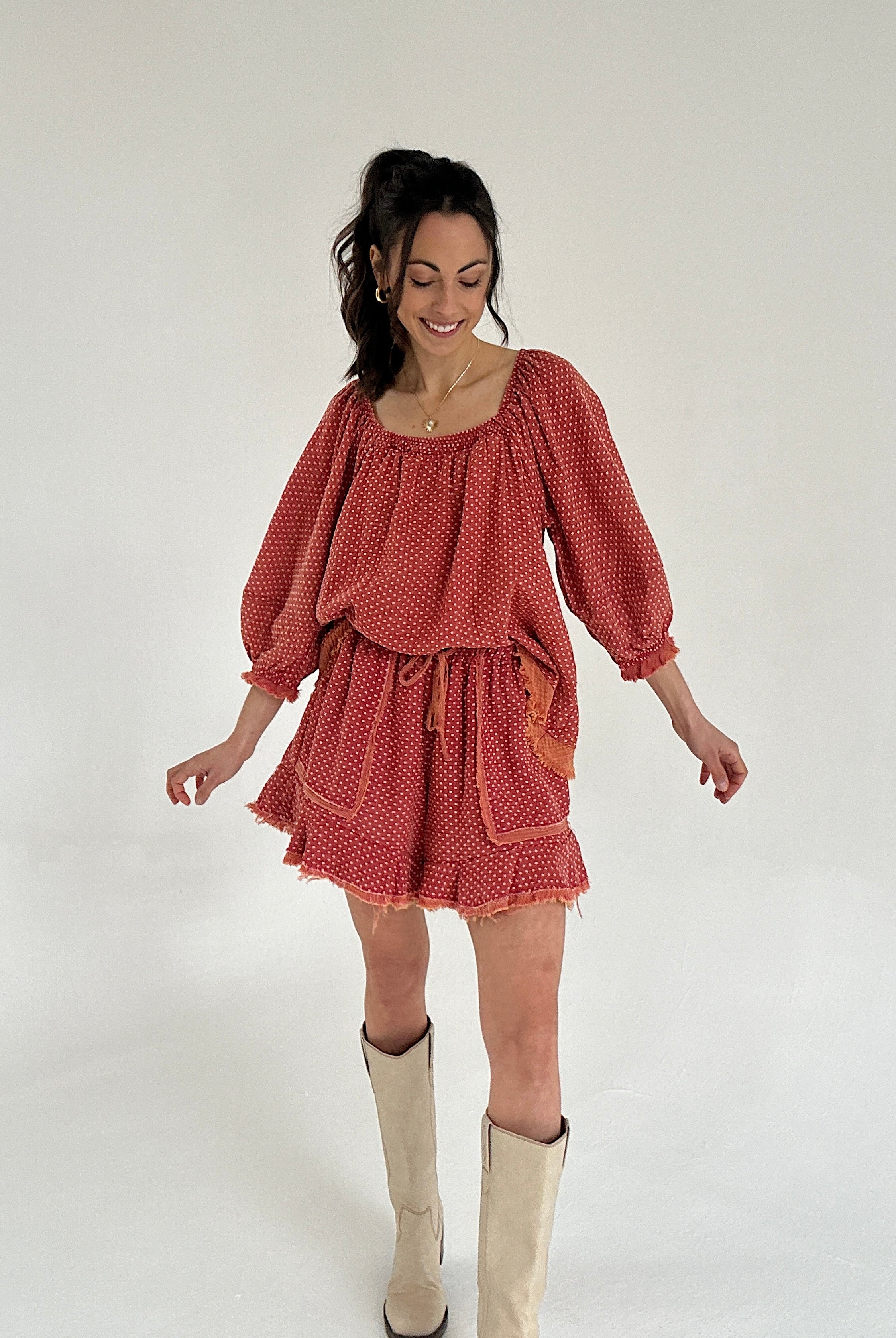 Woman wearing a red set with long sleeves and shorts on a white background