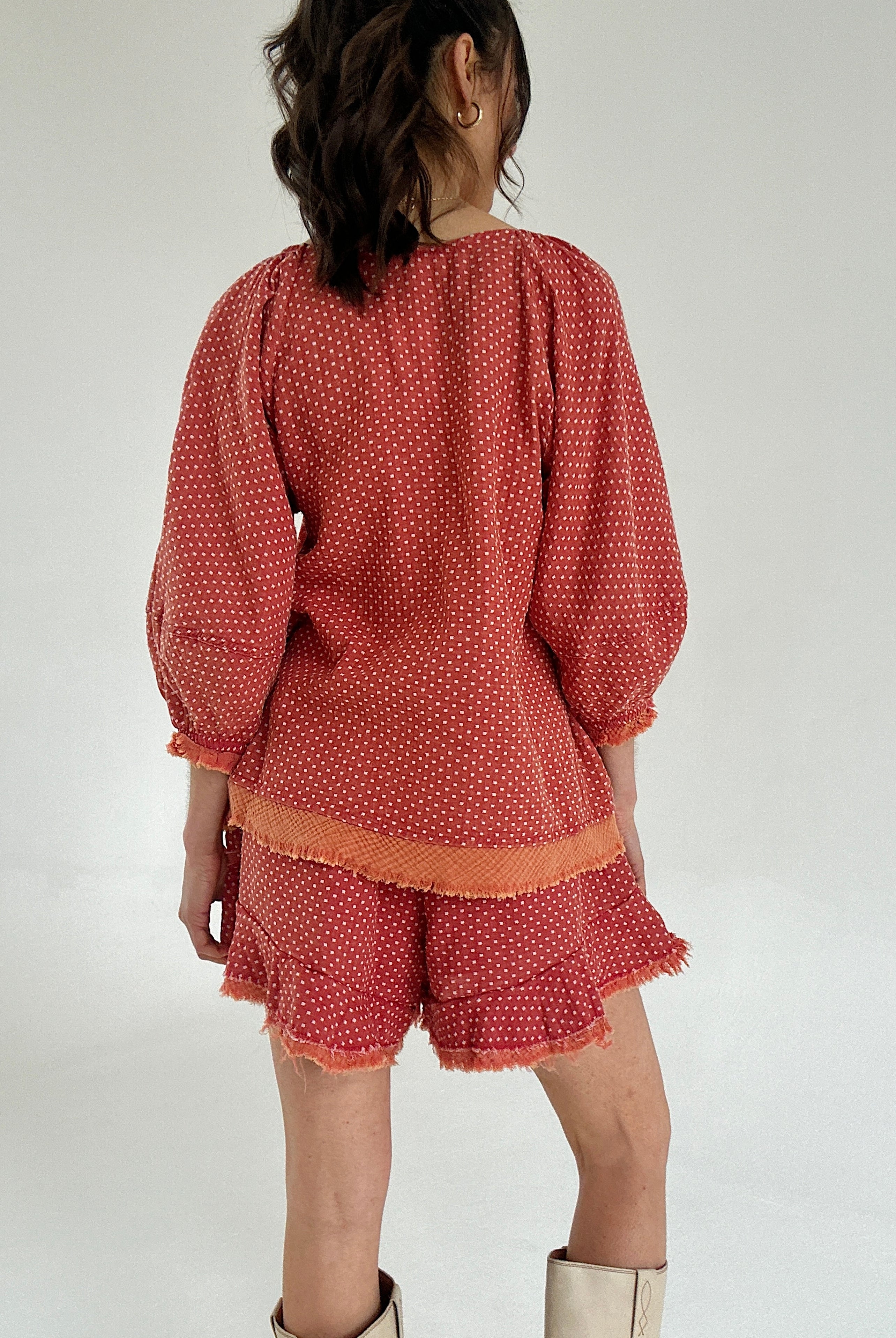 Person wearing a rust-colored polka dot outfit on a white background