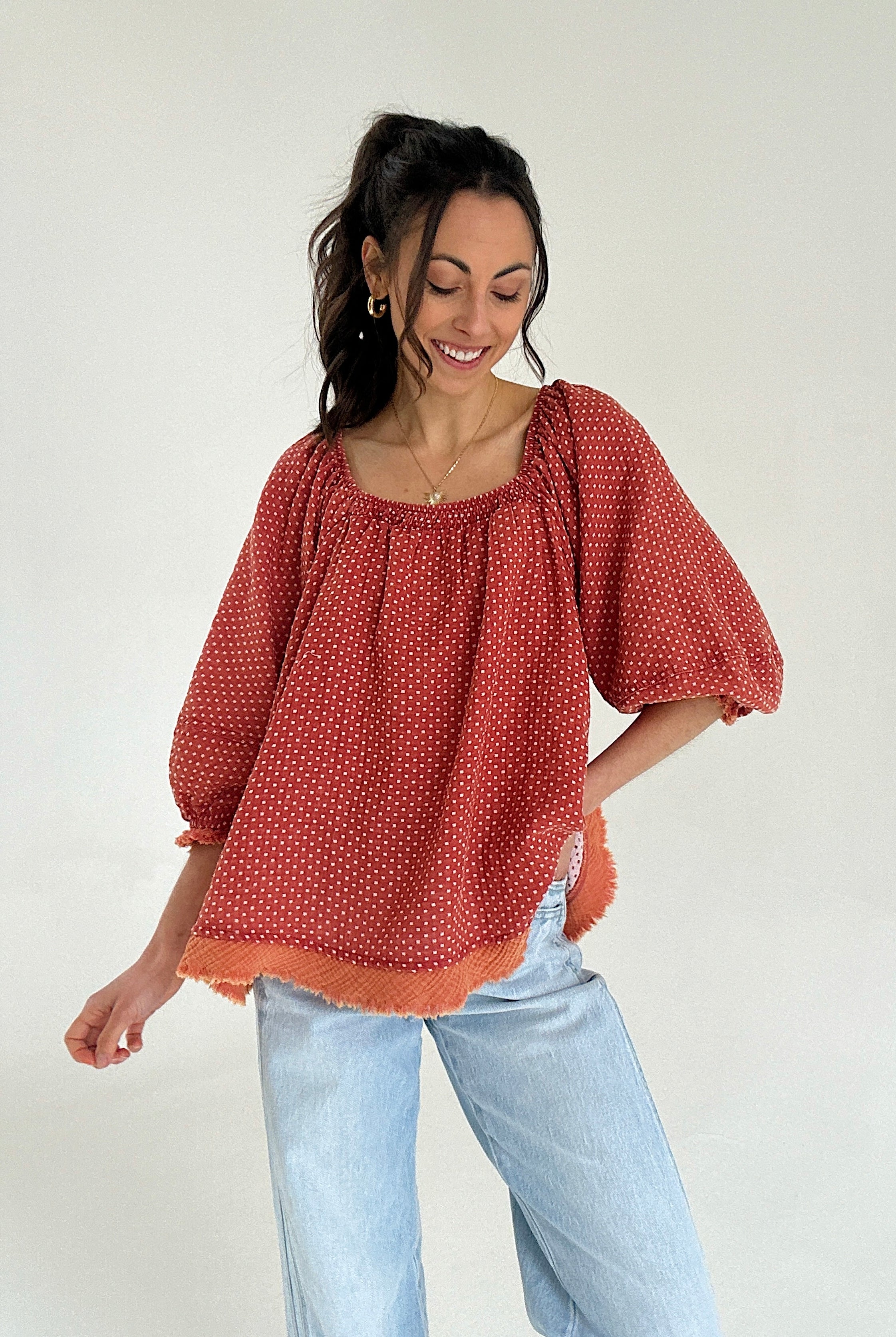 Woman wearing a red polka dot blouse and light blue jeans against a white background