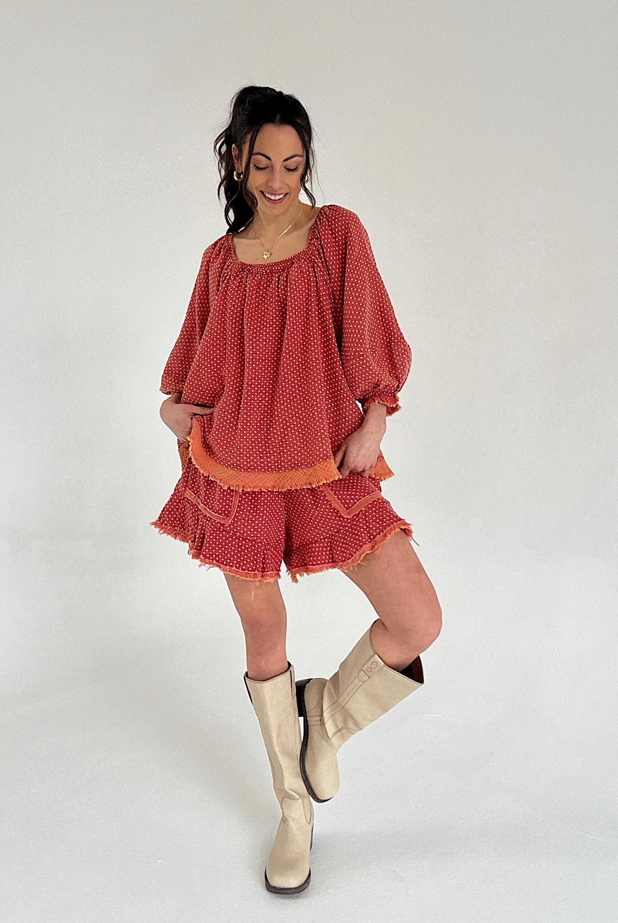 Woman wearing a red matching set and beige boots on a white background