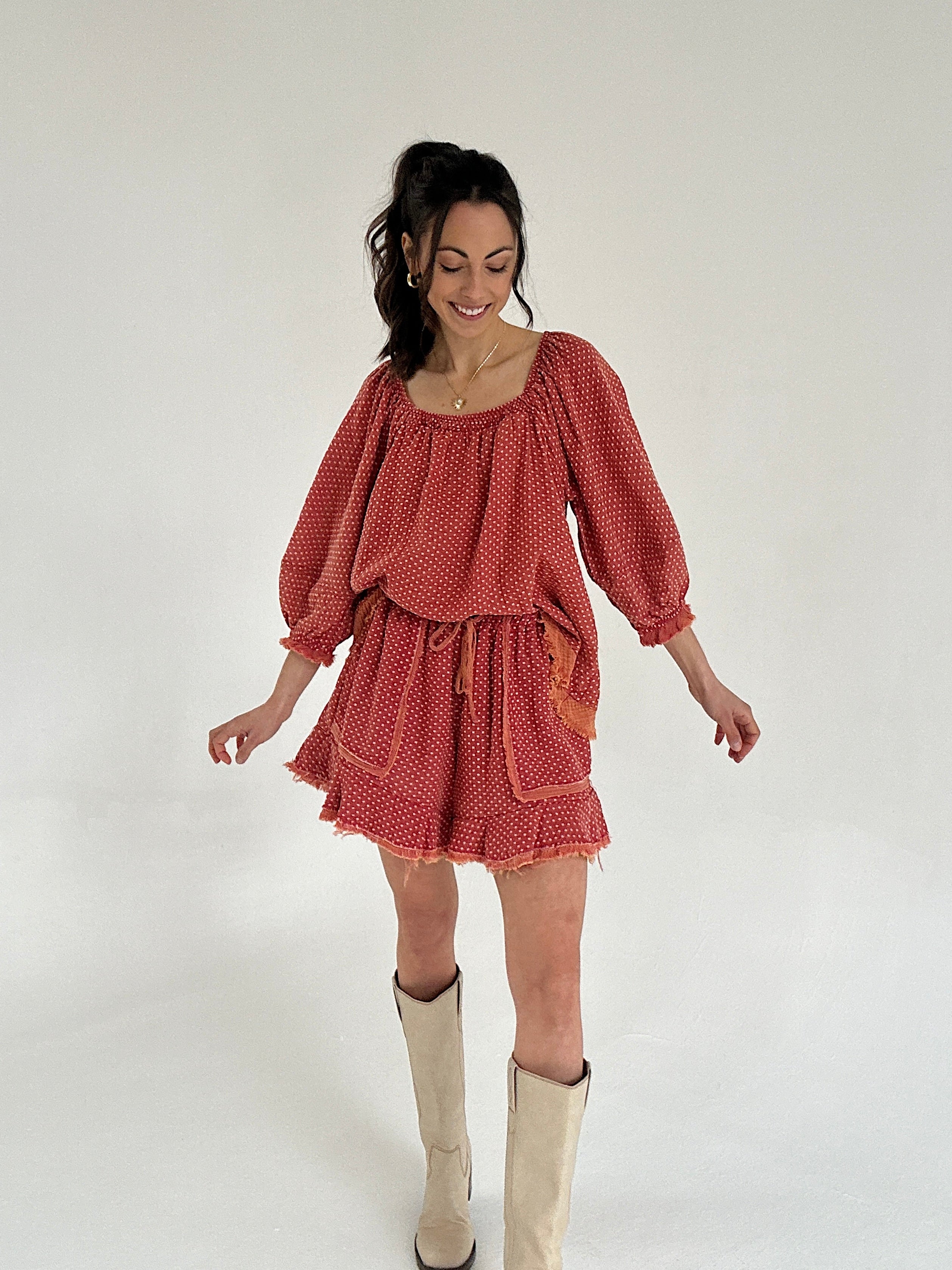 Woman wearing a red set with long sleeves and shorts on a white background