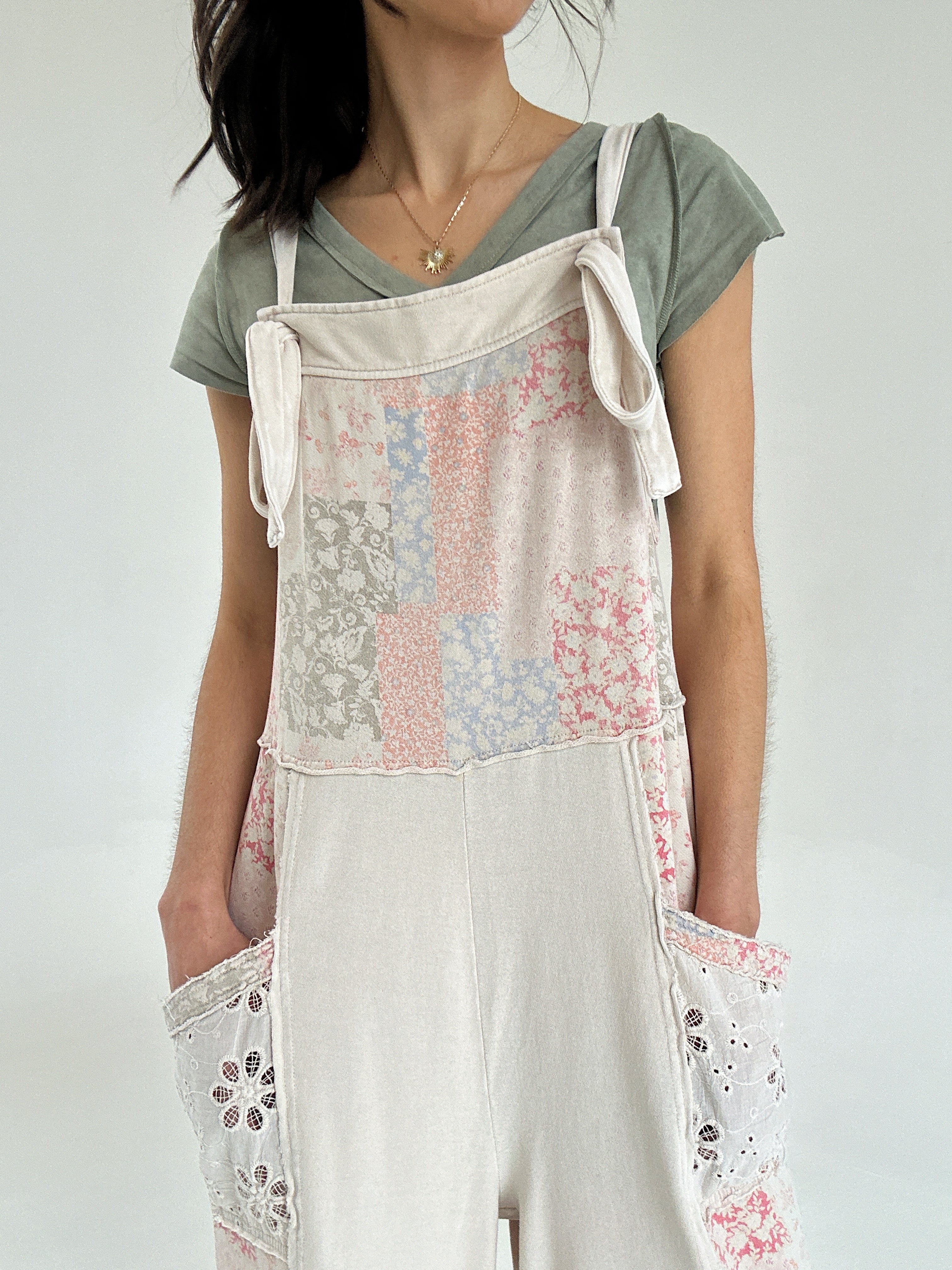 Person wearing a floral patchwork print overall jumper over a green shirt on a white background