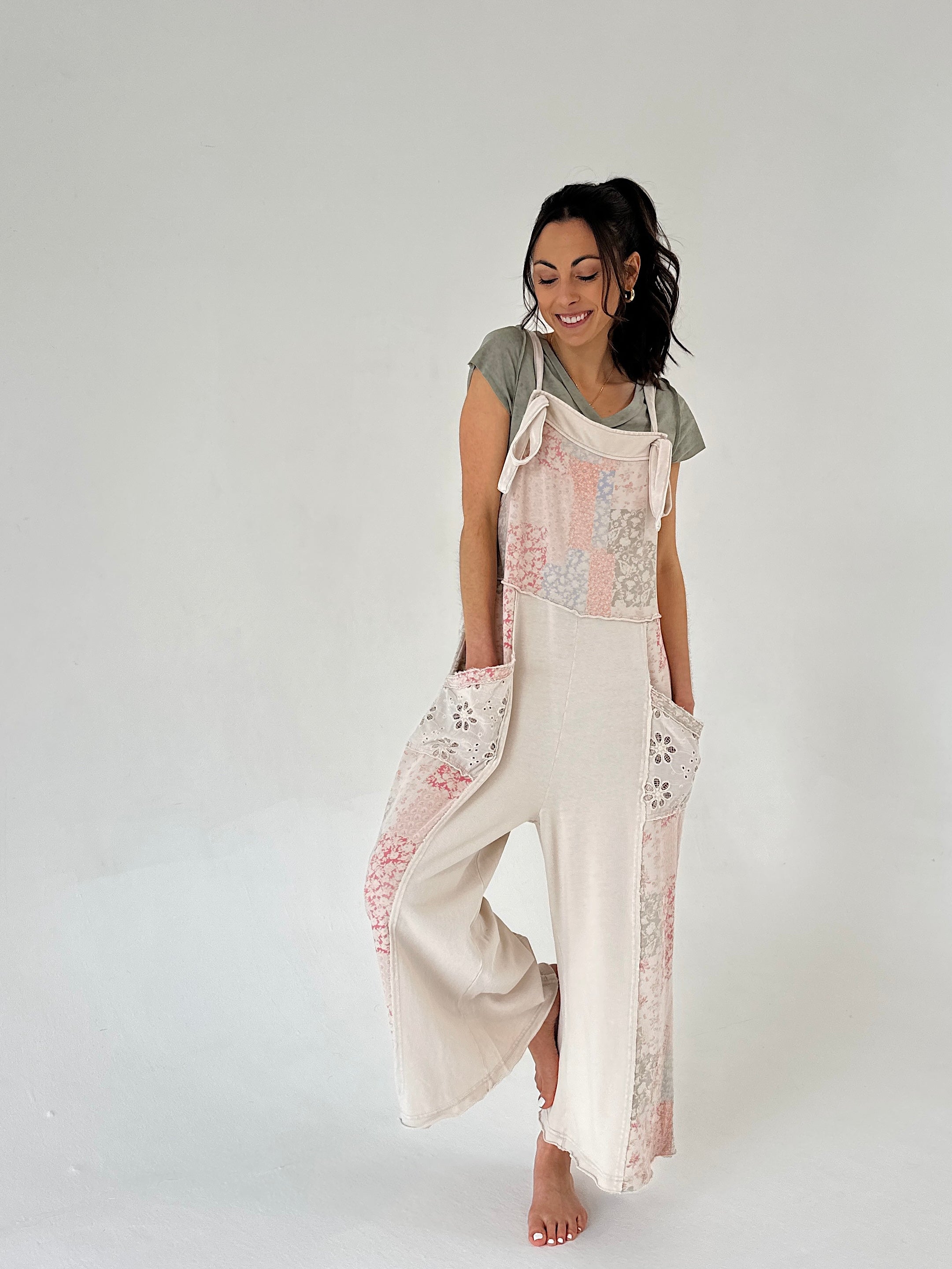 Woman wearing an overall style jumper with patchwork print against a plain background