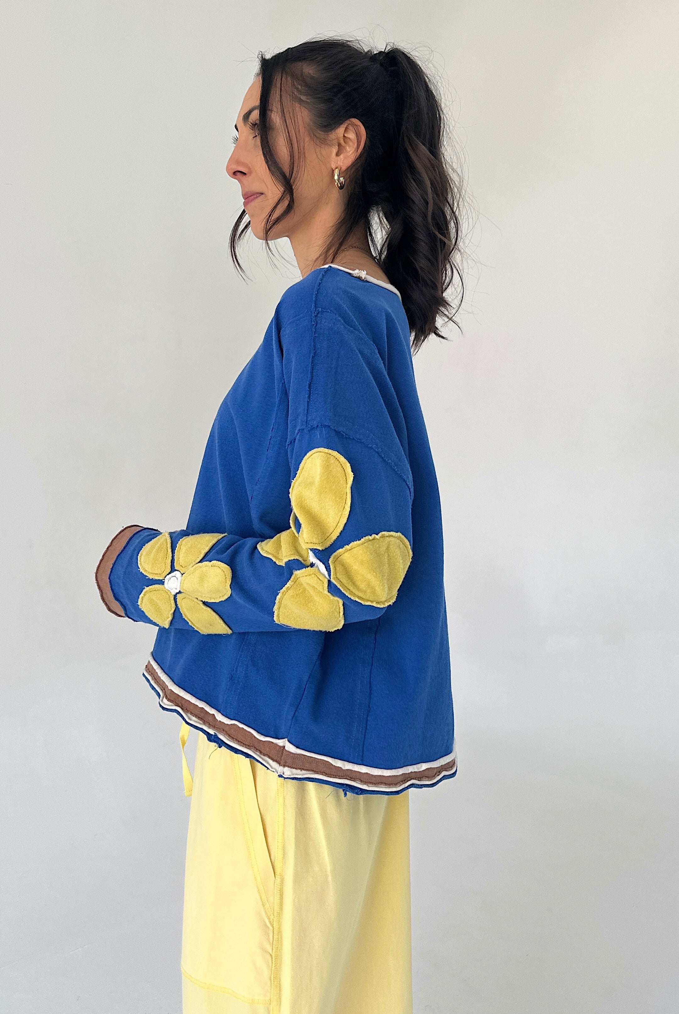 Person wearing a blue sweater with yellow floral patterns on a plain background