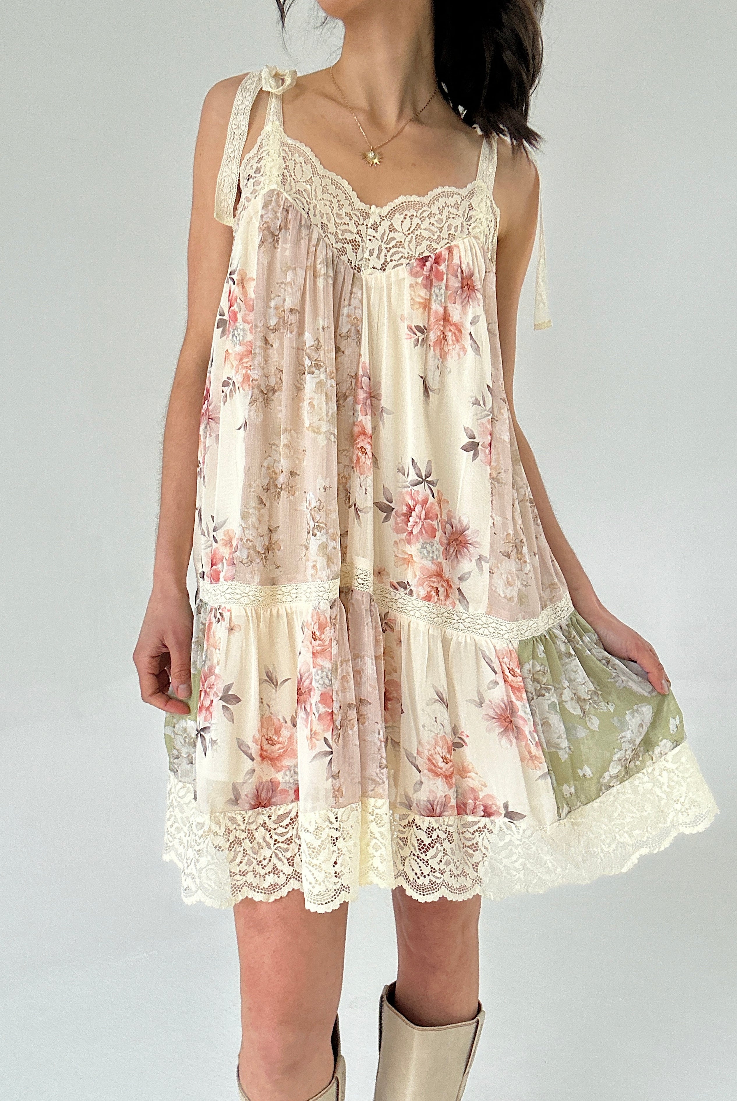 Woman wearing a floral dress with lace details on a plain background