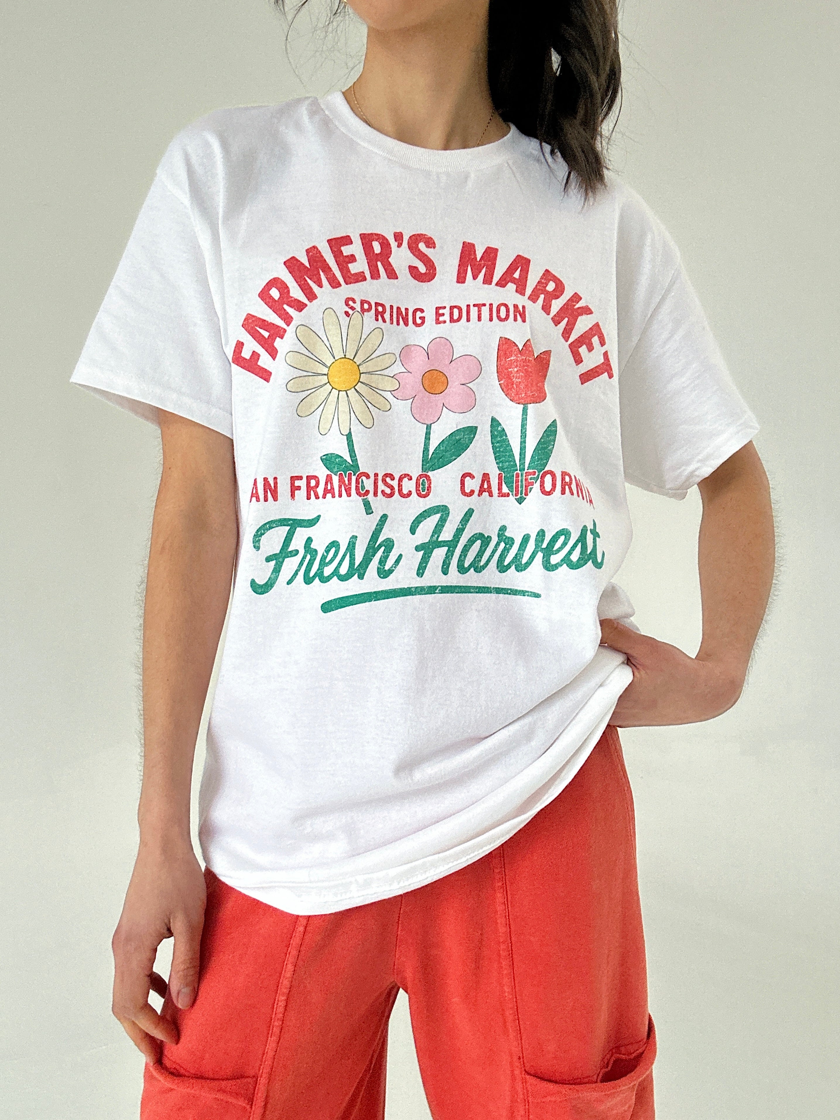 Person wearing a white t-shirt with 'Farmer's Market Spring Edition' design.