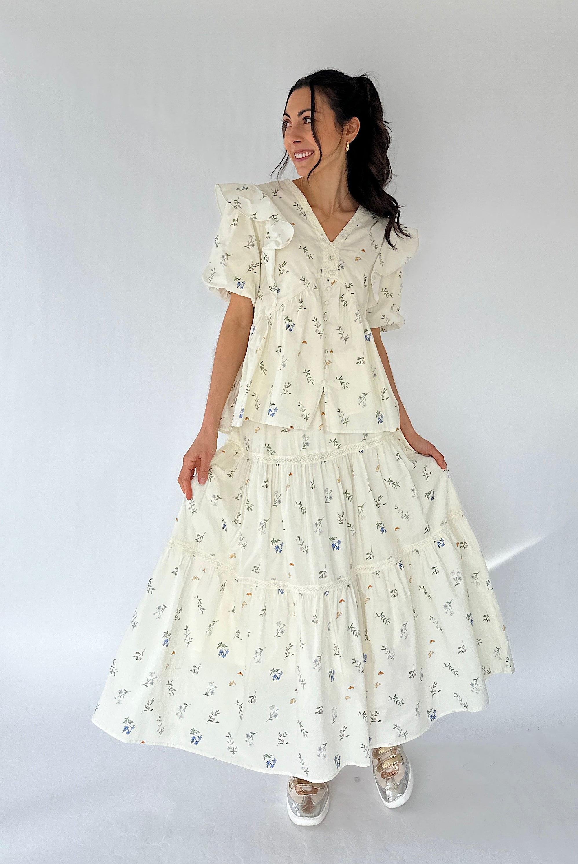 Woman wearing a floral maxi skirt and matching top against a white background