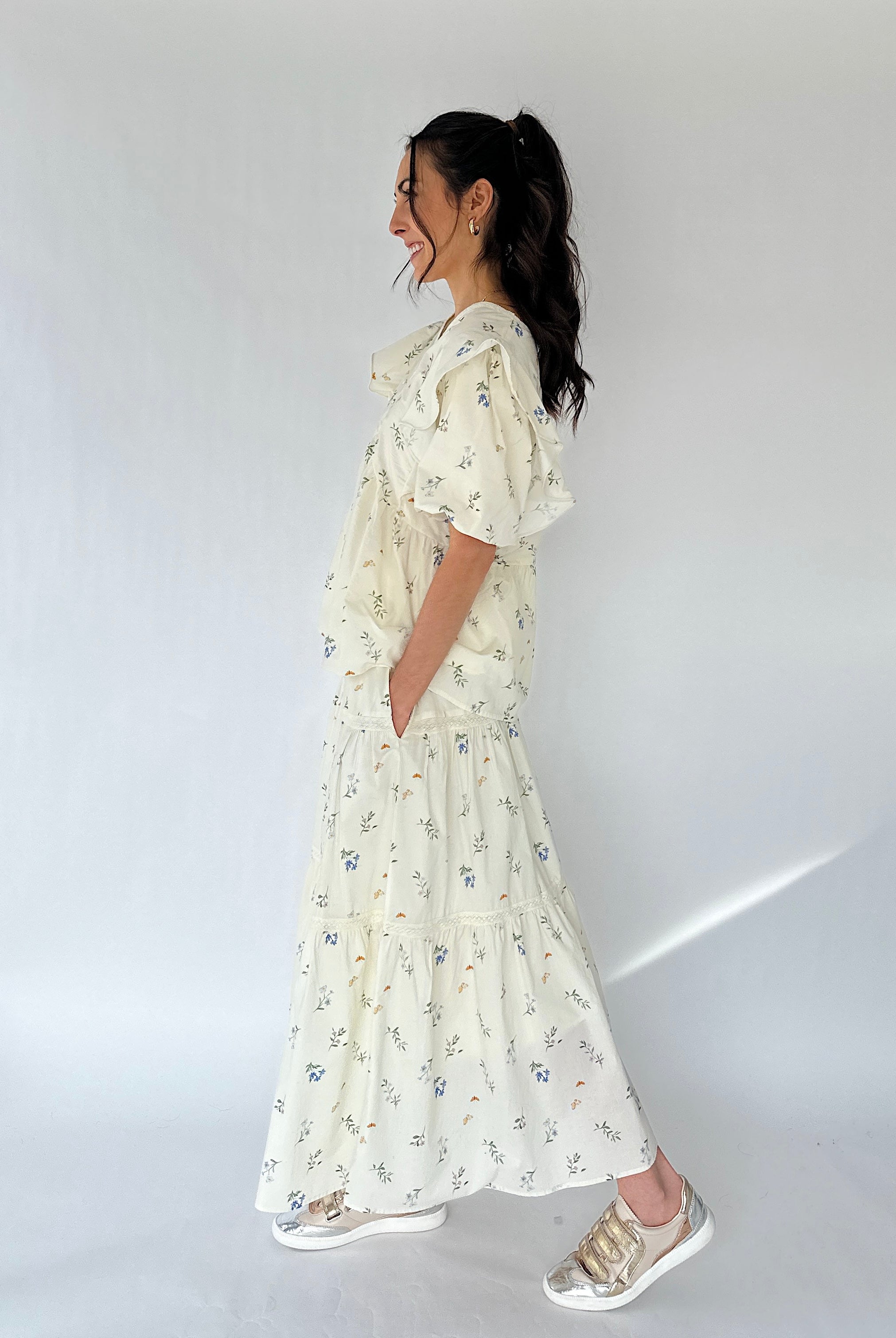 Woman wearing a white maxi skirt and matching top against a plain background