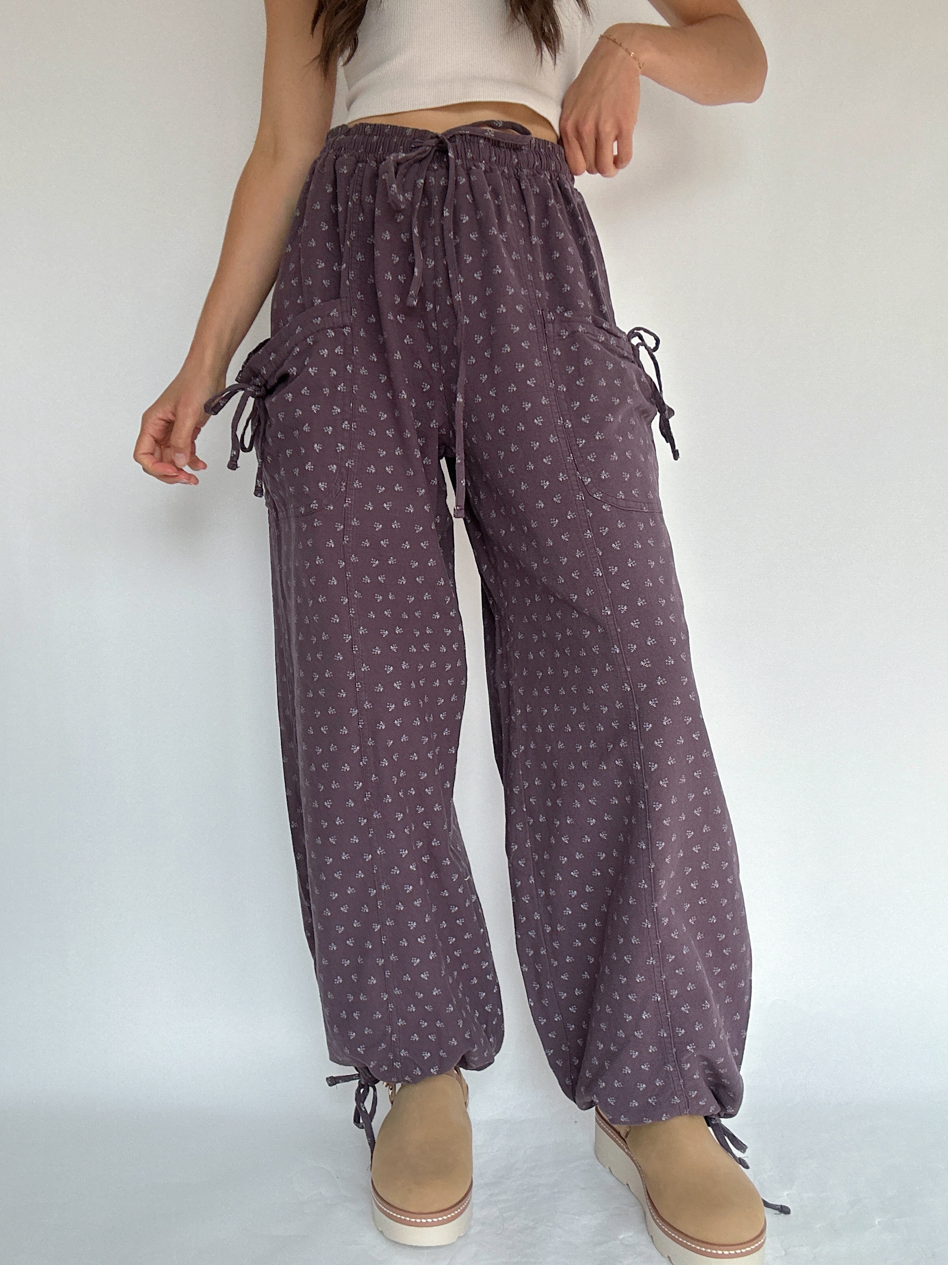 Person wearing purple patterned pants with a white background