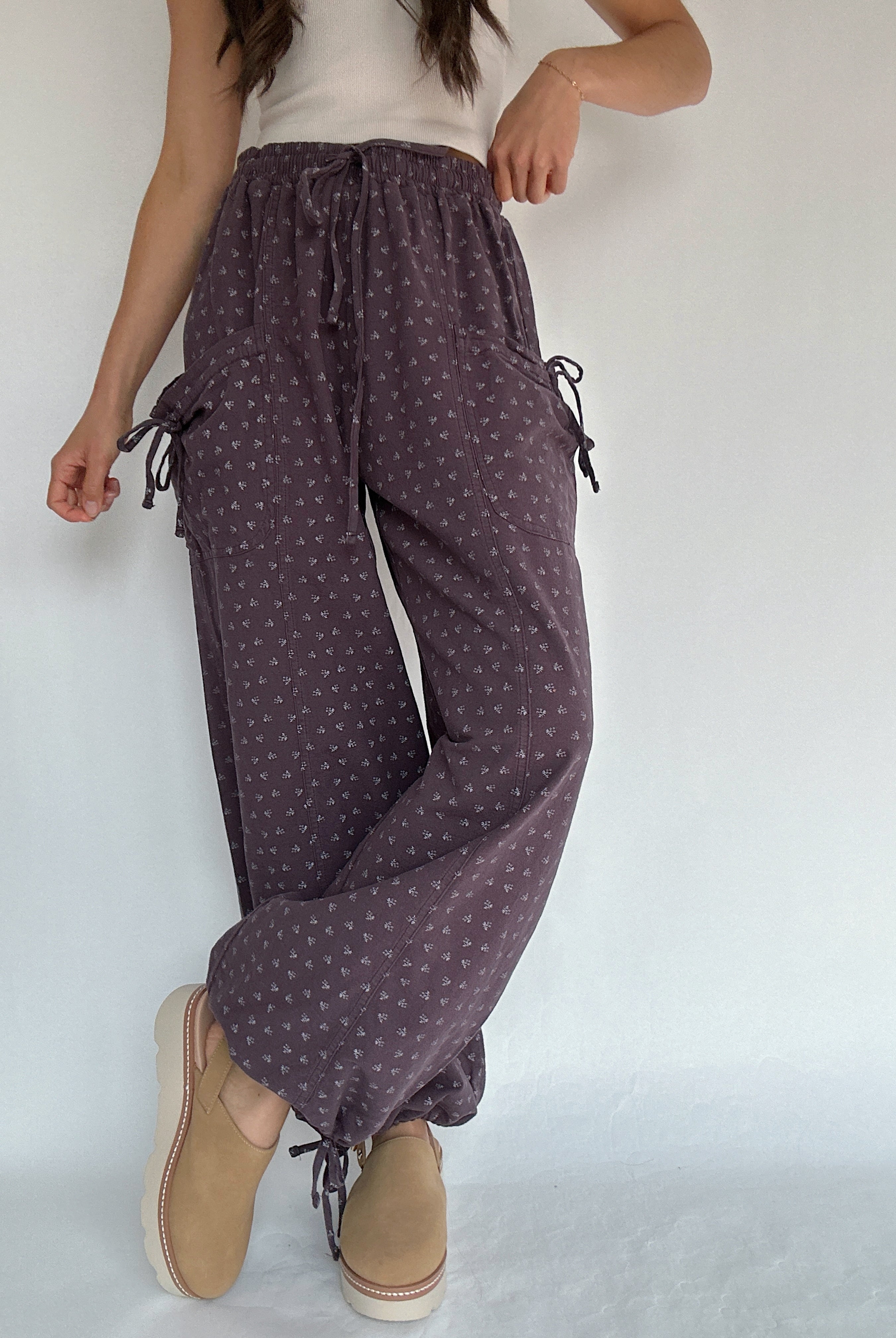 Person wearing purple polka dot pants with a white background with legs crossed