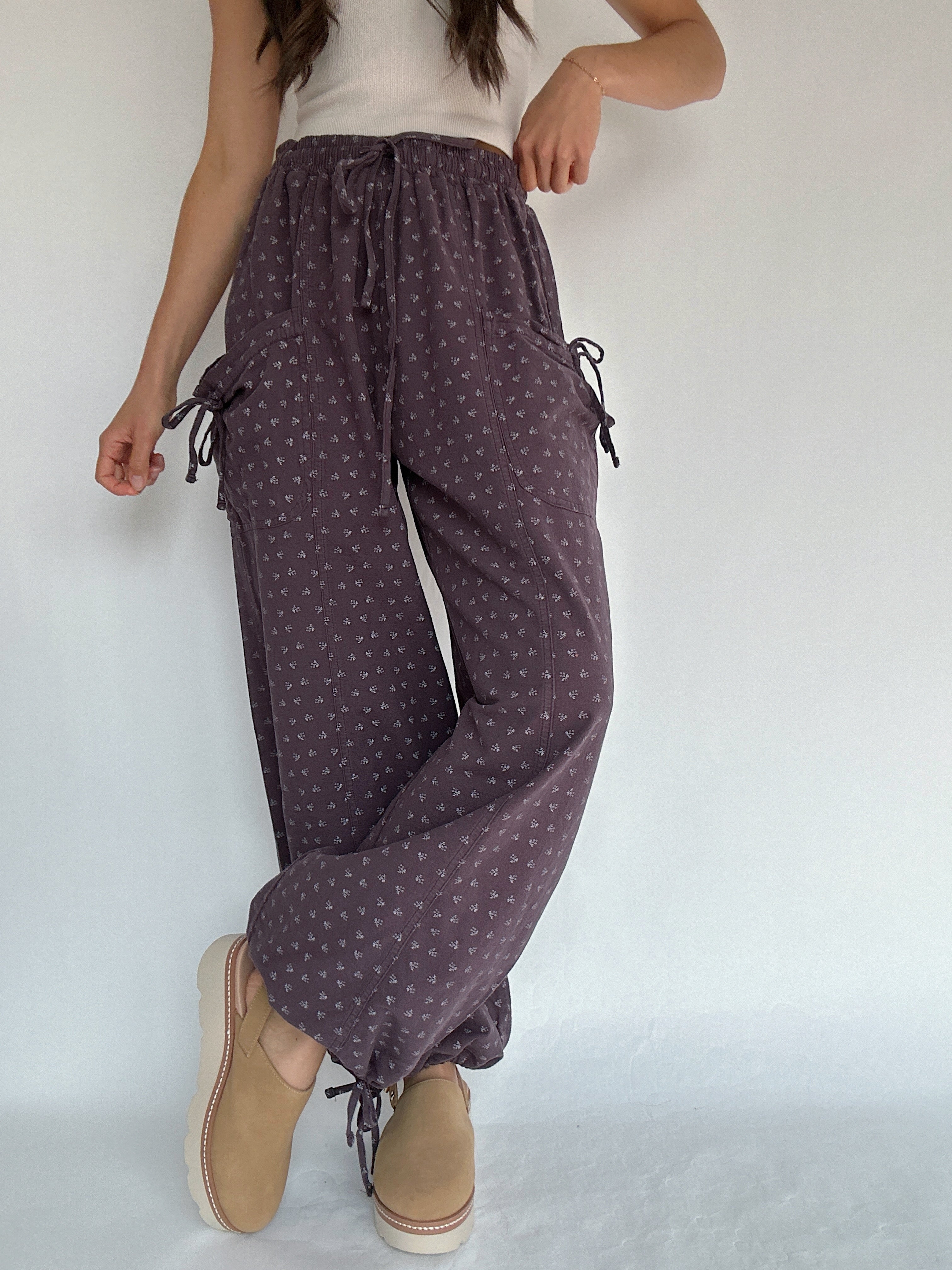 Person wearing purple polka dot pants with a white background with legs crossed