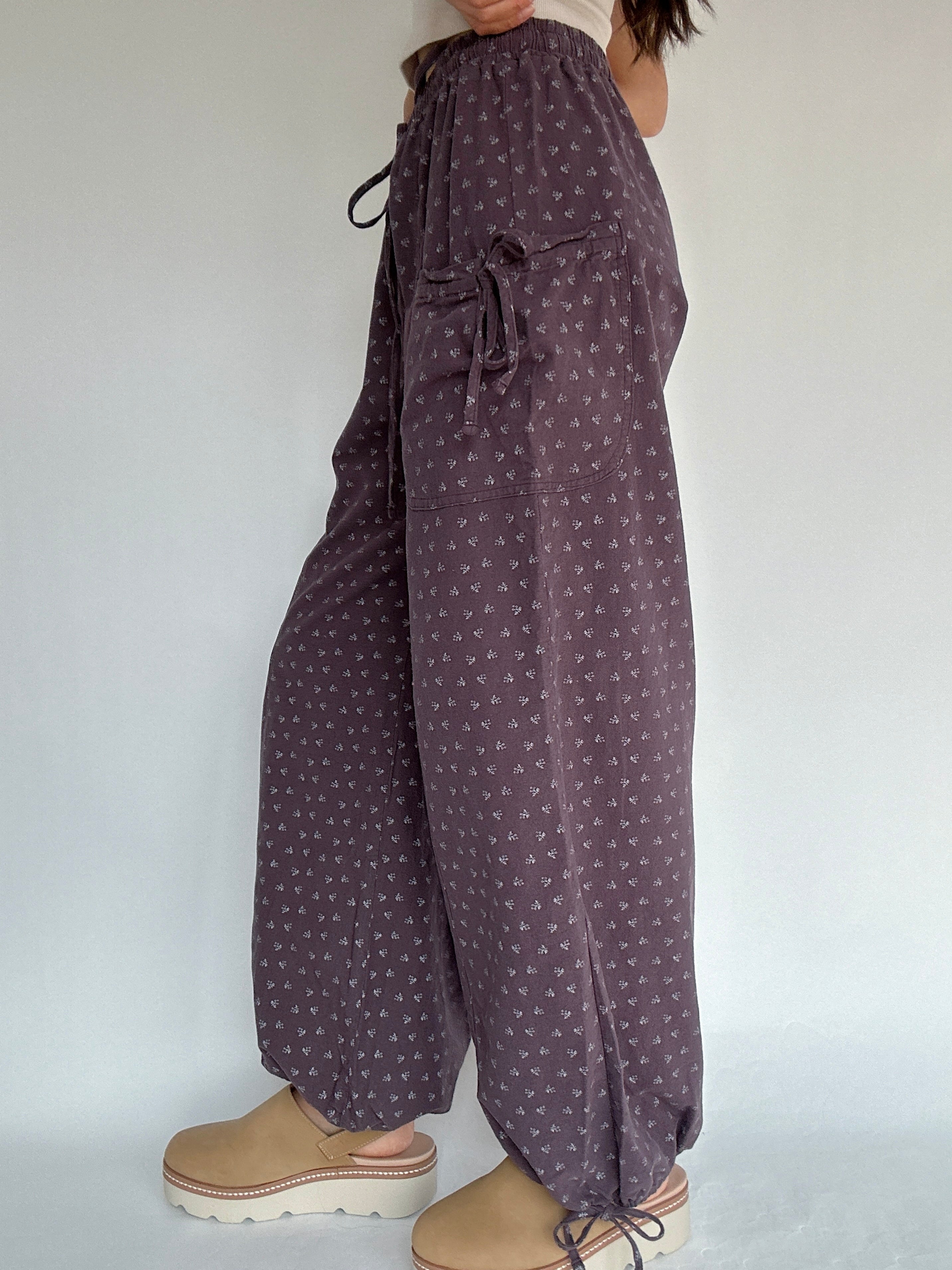 Purple patterned pants worn by a person on a plain background showing side detail