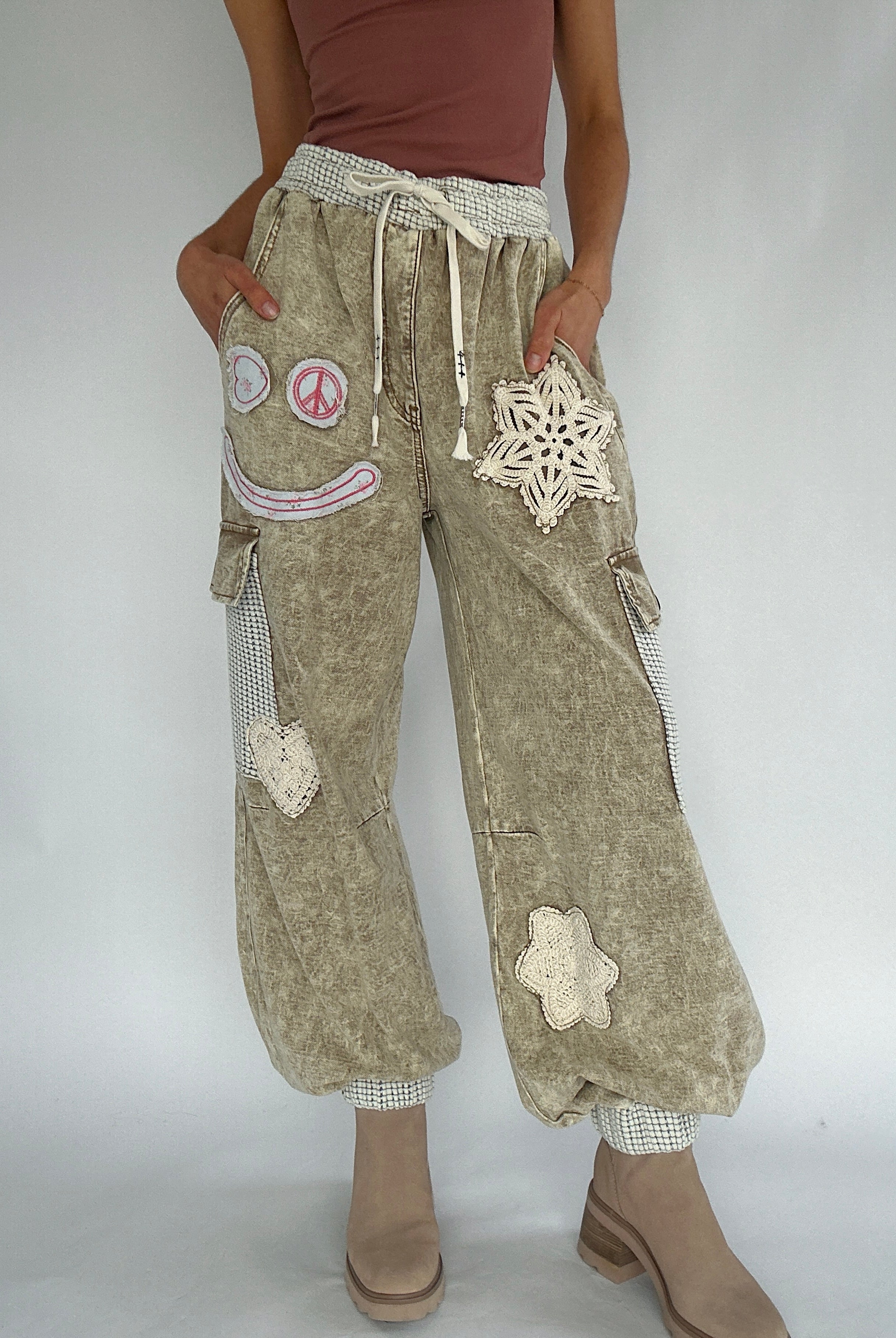 Light brown cargo jogger pants with decorative patches on a plain background