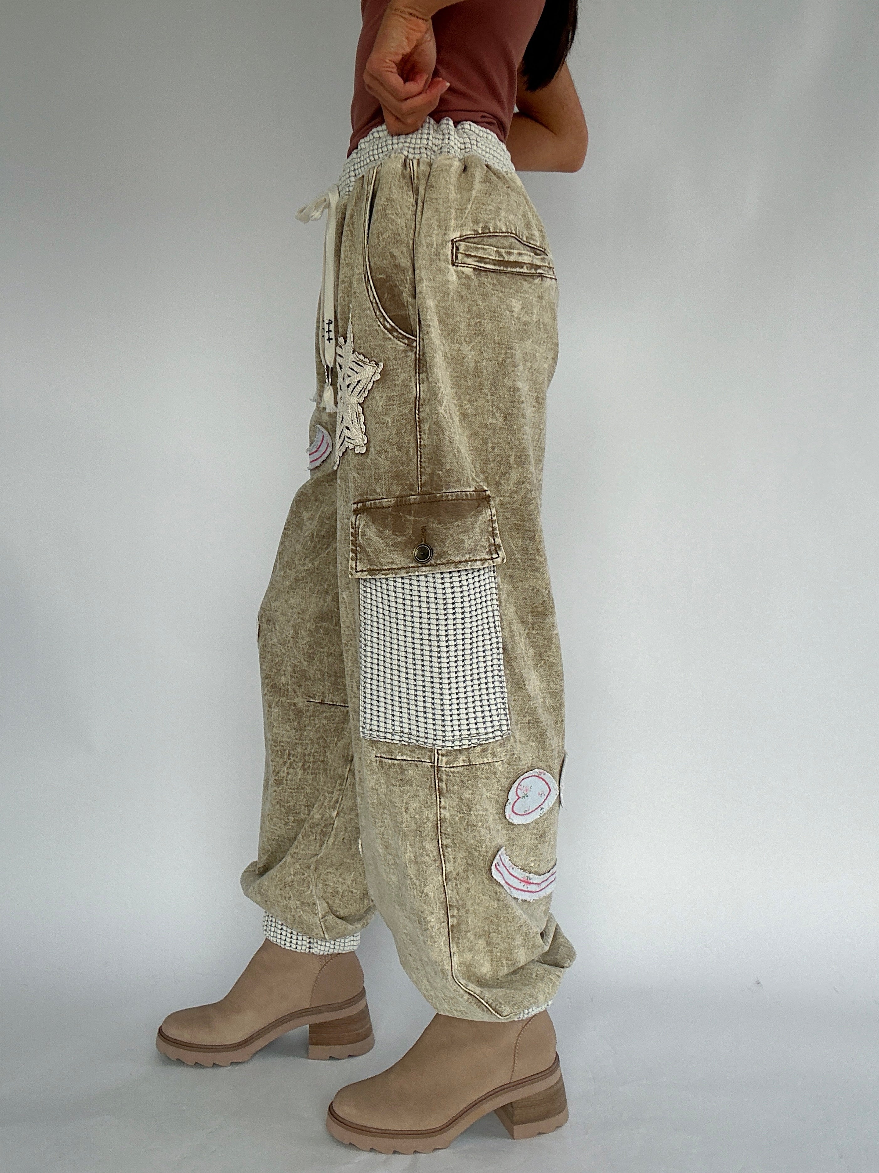 Beige patchwork cargo jogger pants worn by a person on a plain background from side