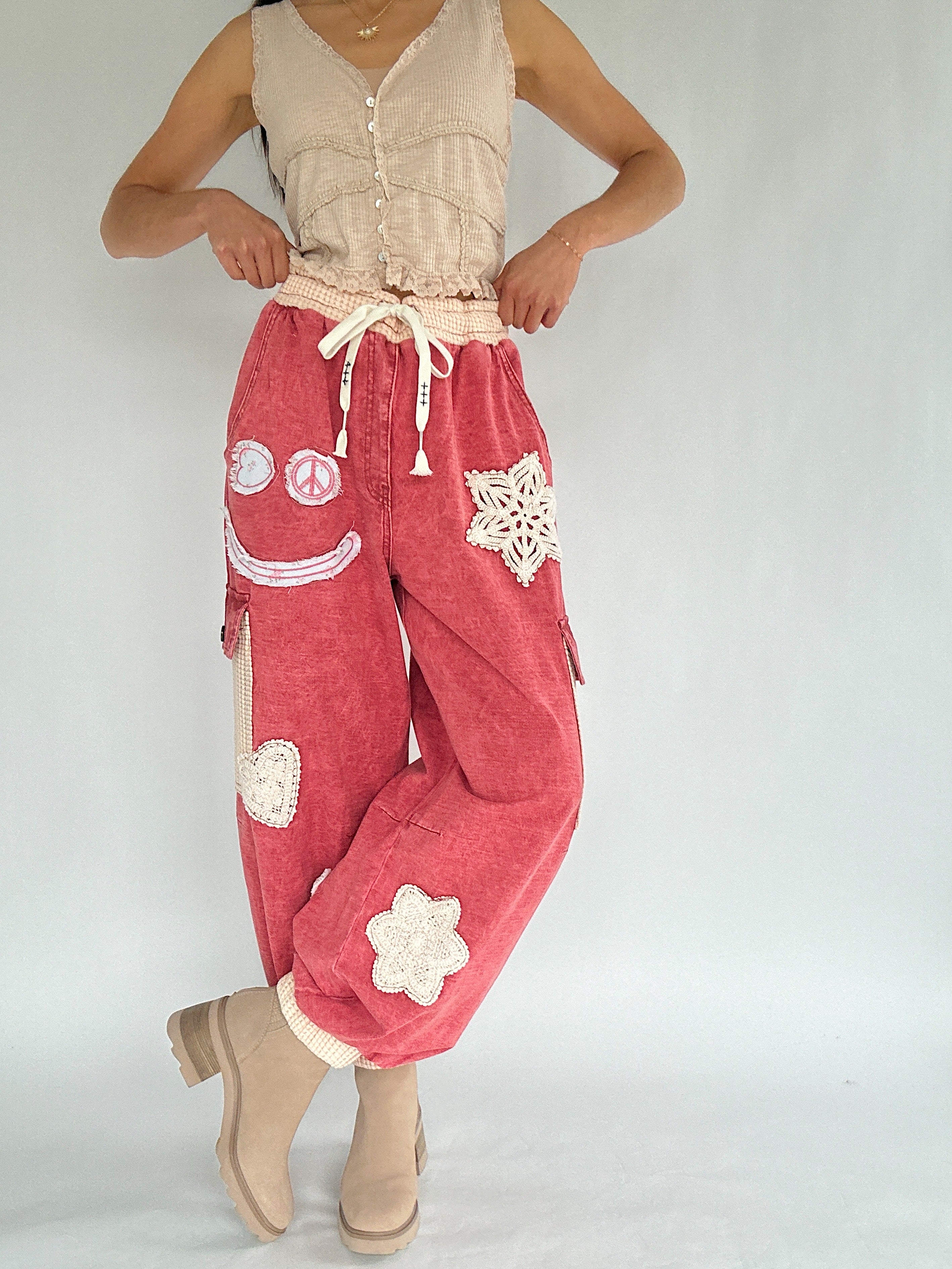 Person wearing red pants with white floral and peace symbol designs on a plain background