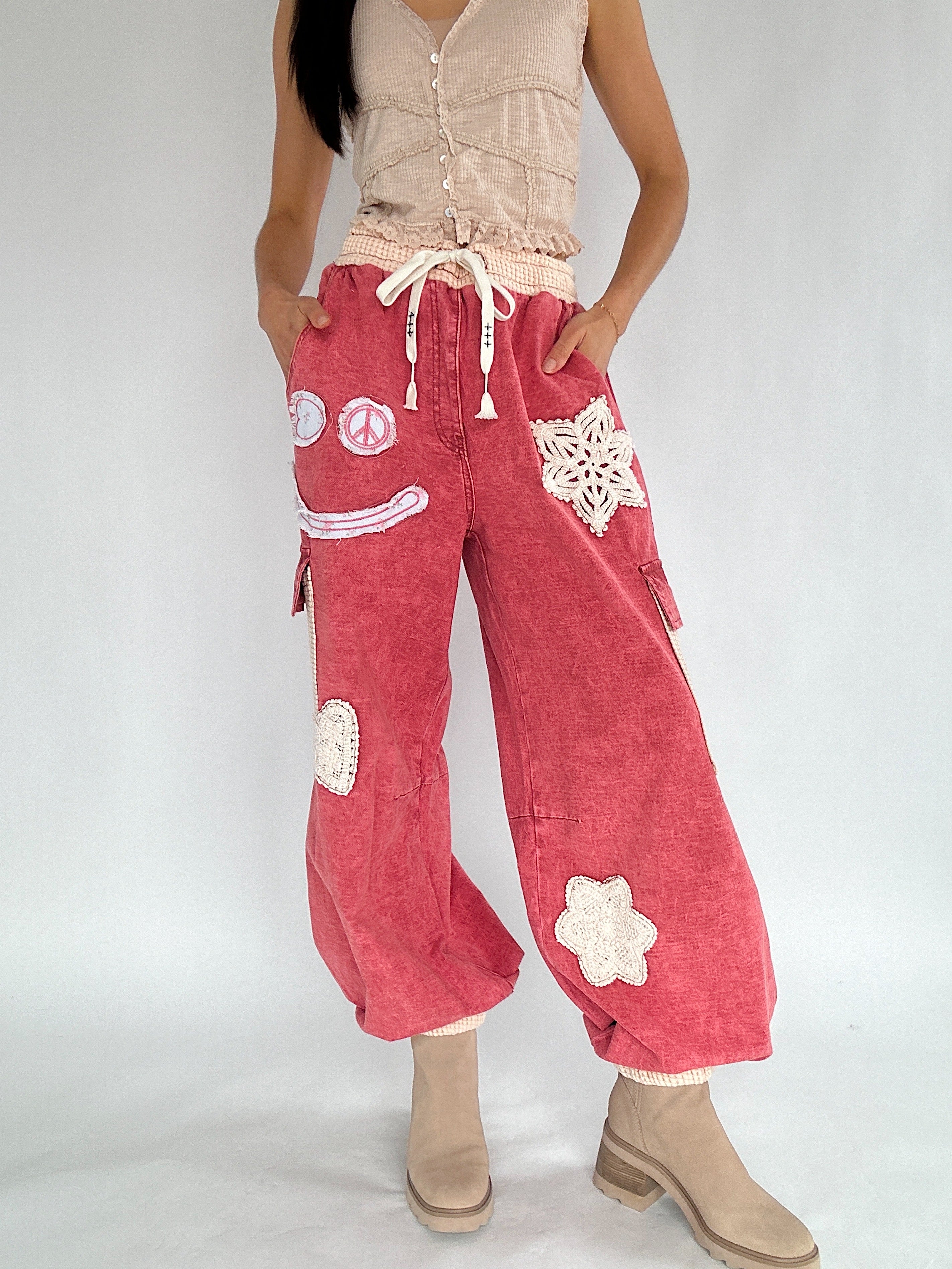 Person wearing red pants with white patterns on a plain background