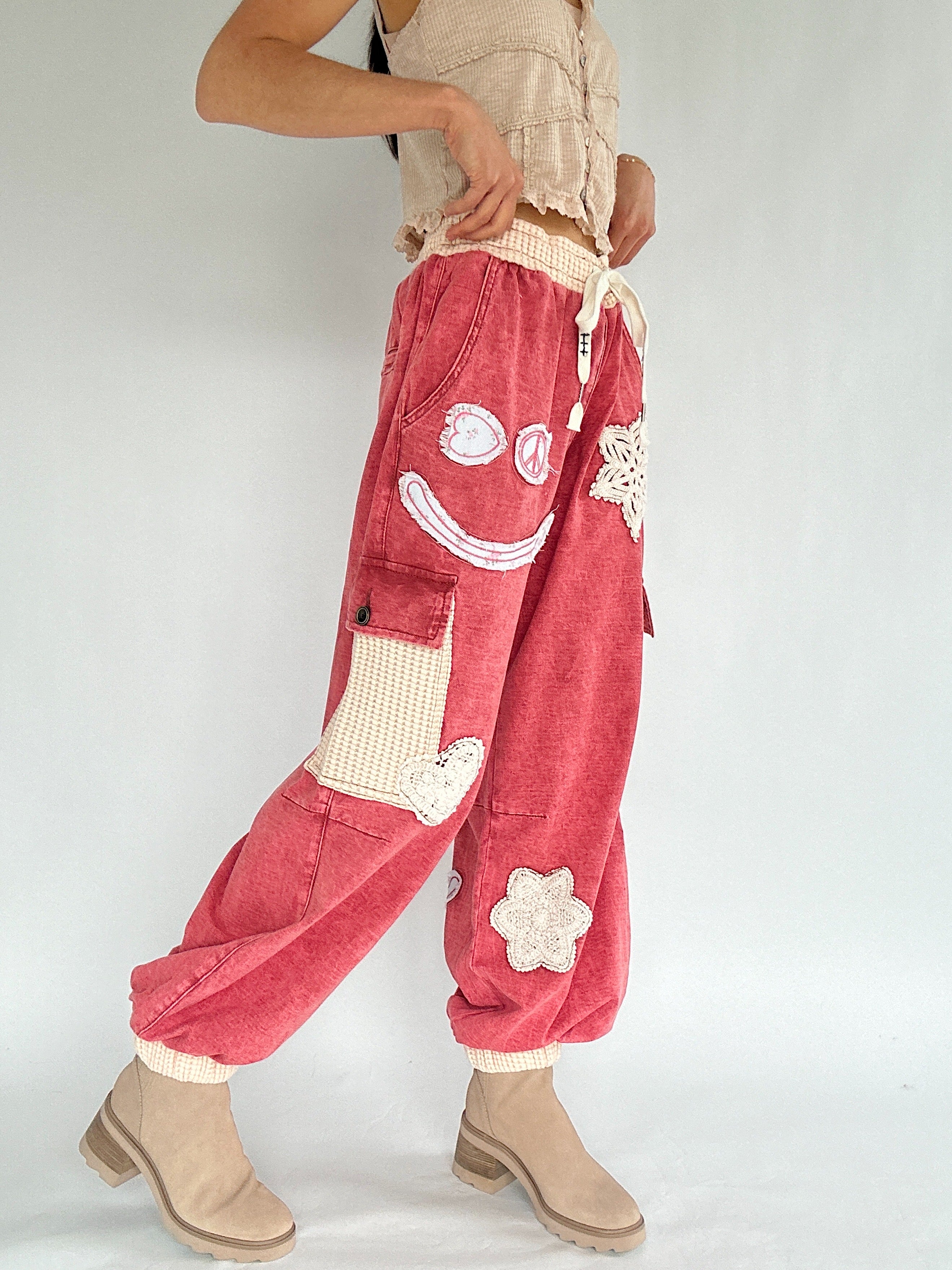 Person wearing red pants with smiley face and flower designs on a plain background