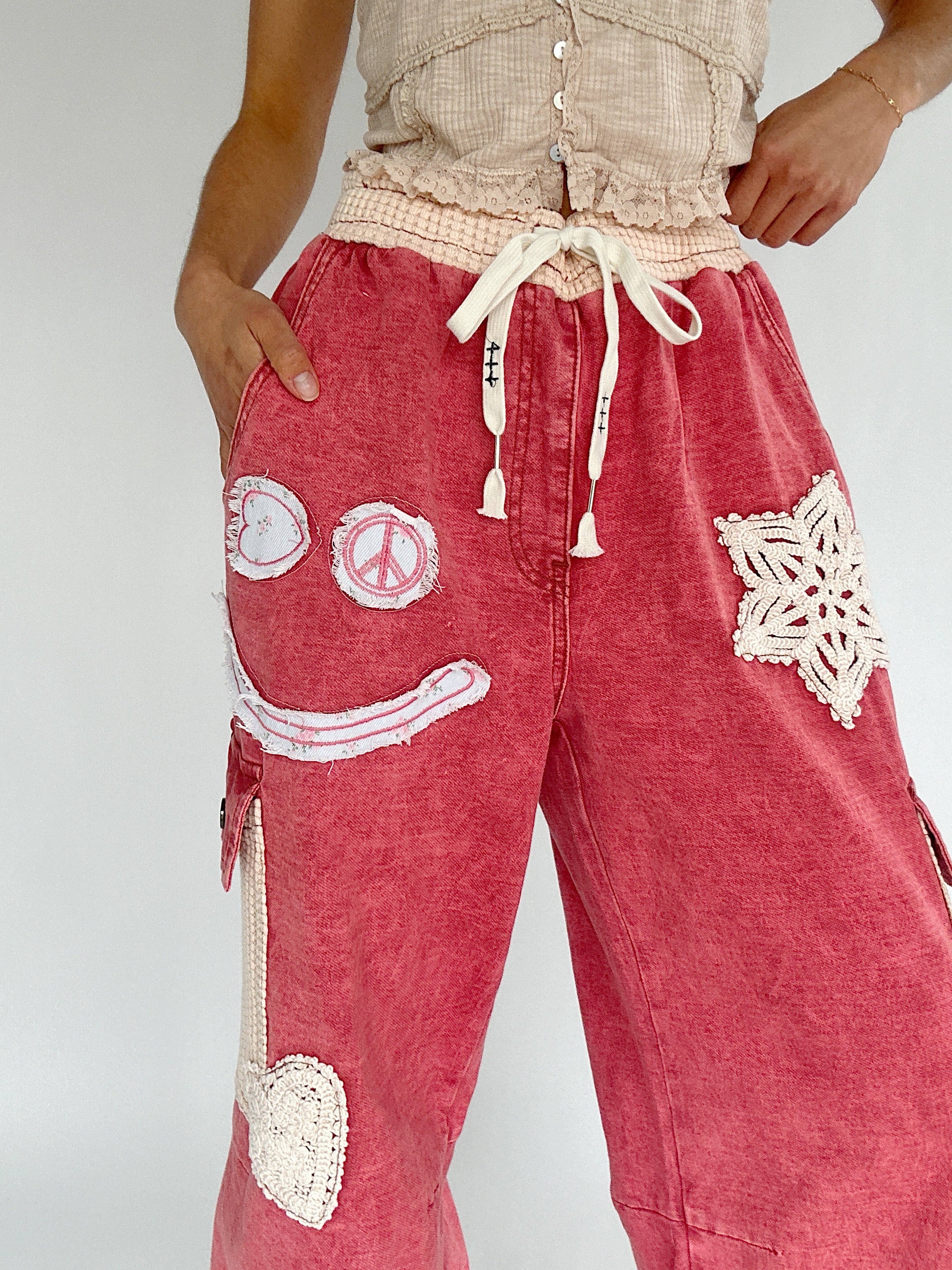Red pants with white patches and designs on a plain background
