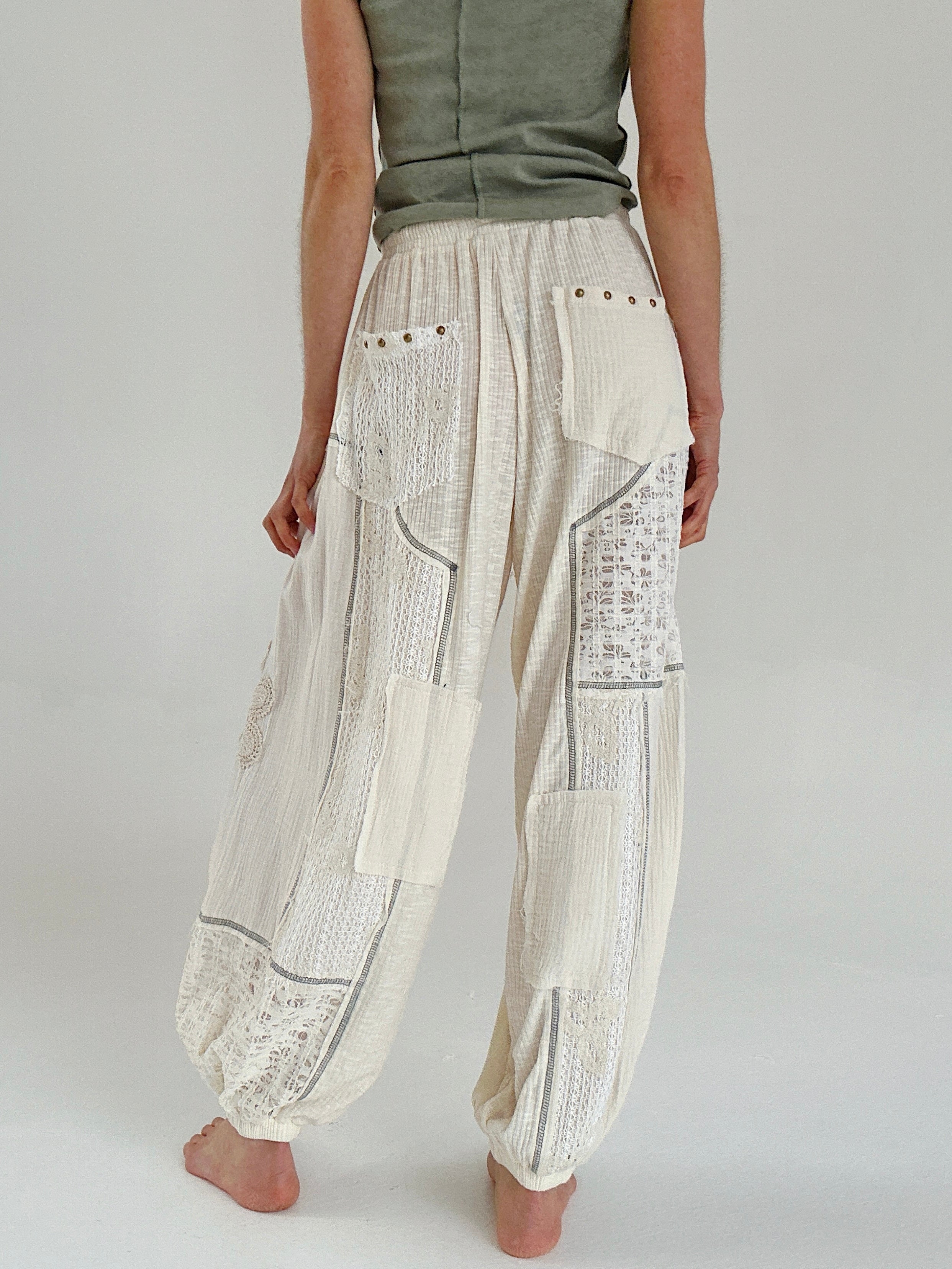 Person wearing cream patchwork pants on a plain background showing back pocket details