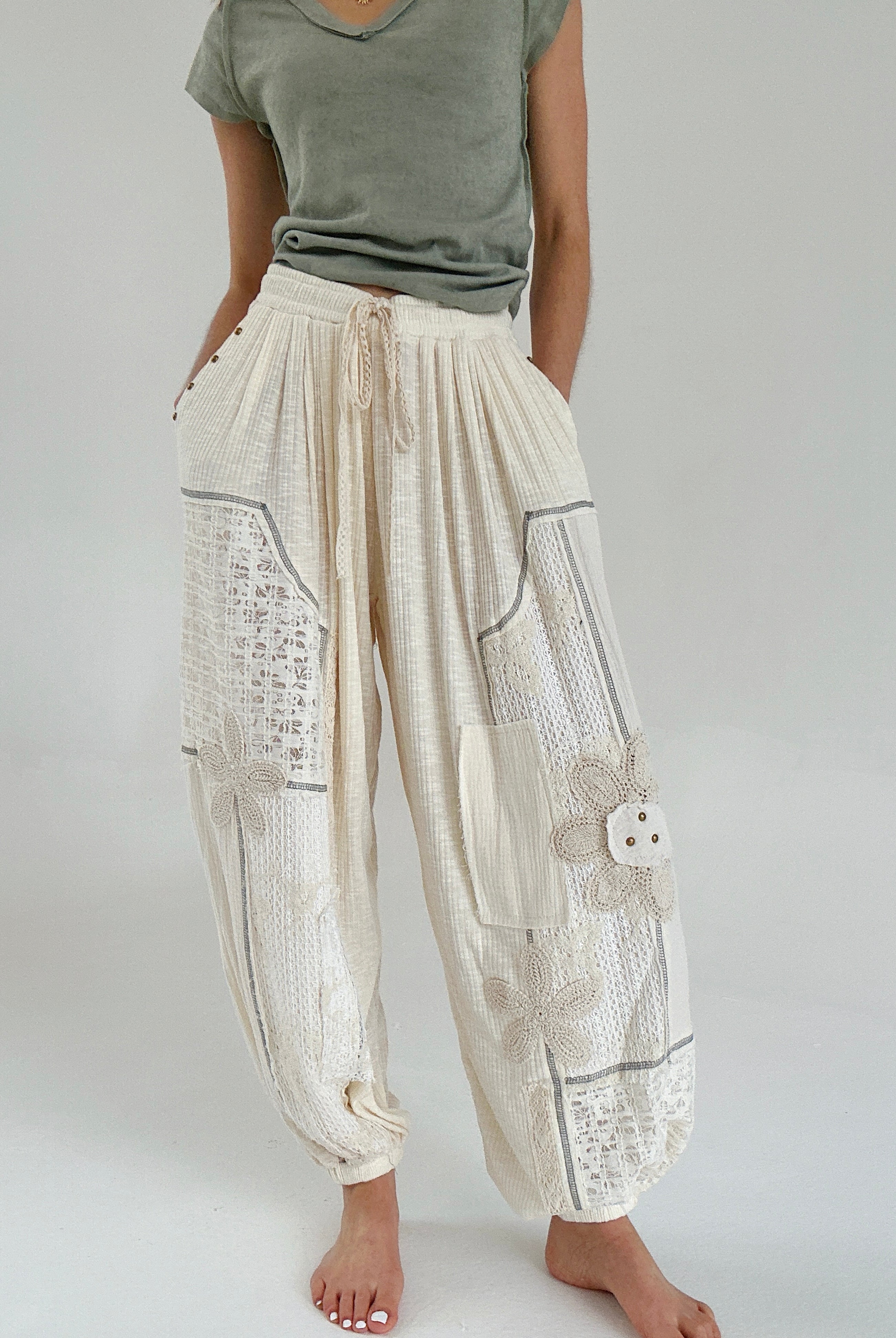 Person wearing beige patchwork jogger pants with a plain background