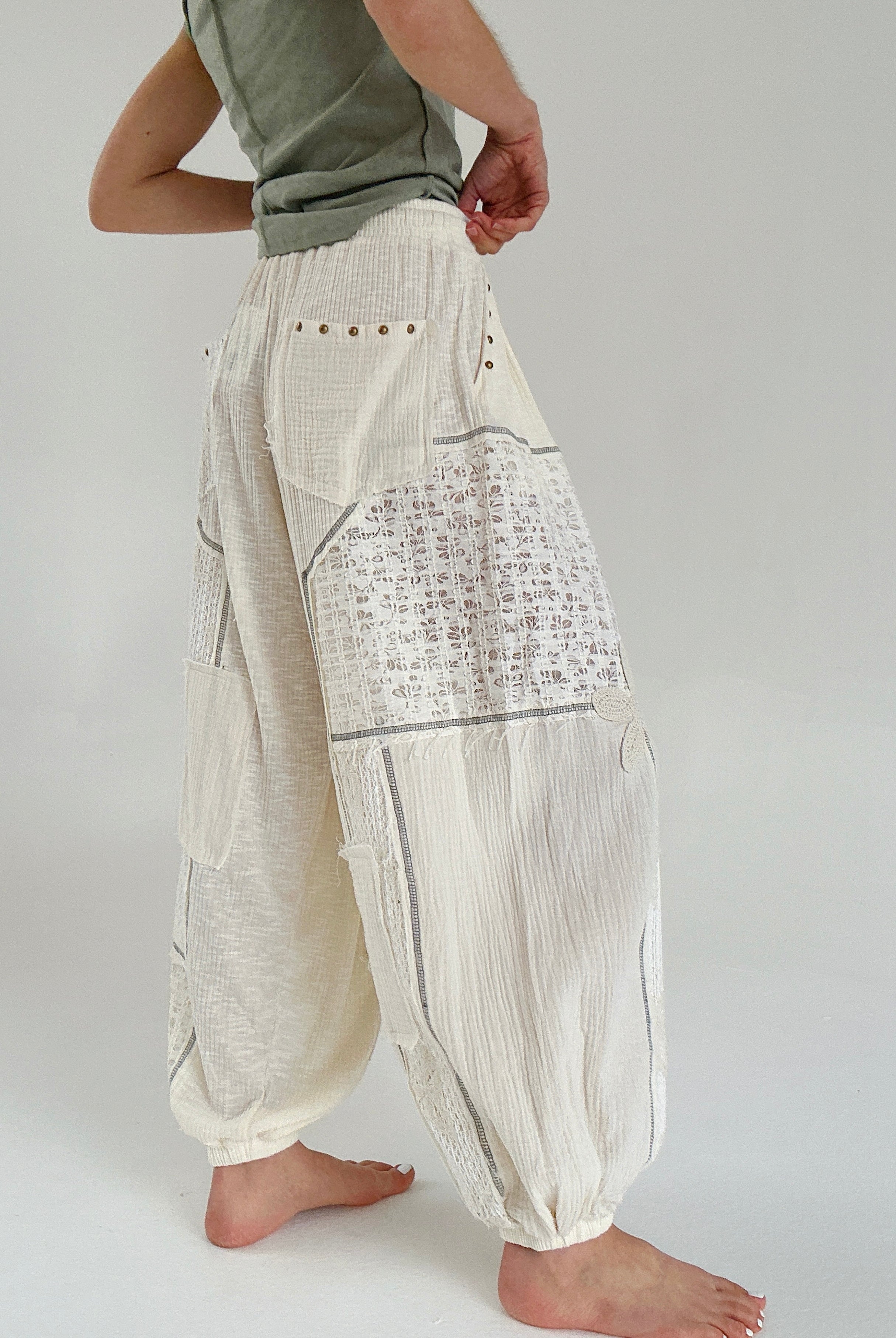 Person wearing light-colored harem pants with a subtle pattern on a plain background