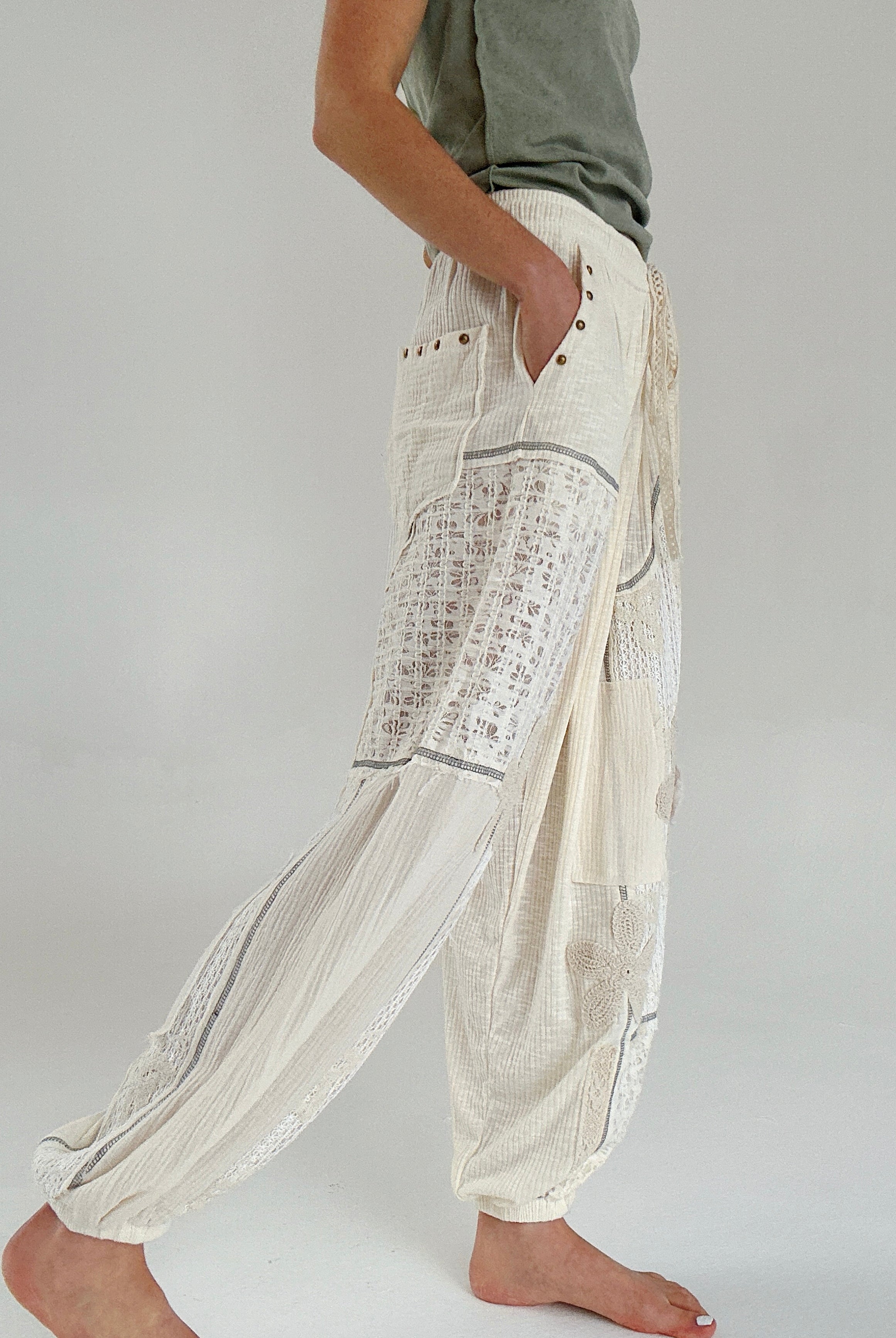 Person wearing cream wide-leg jogger pants with text pattern on a plain background showing side pockets