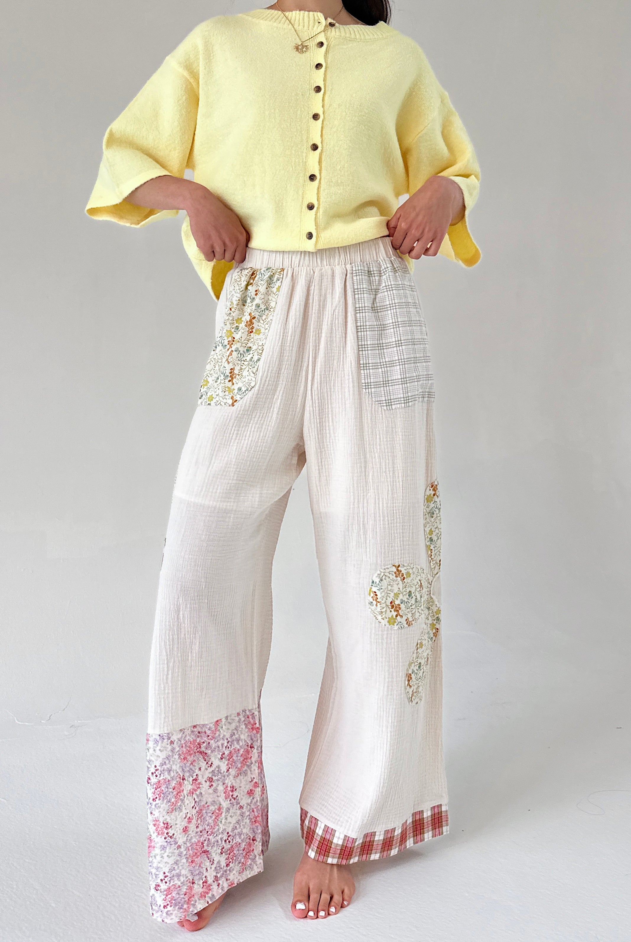 Person wearing a yellow top and white pants with floral patterns on a plain background