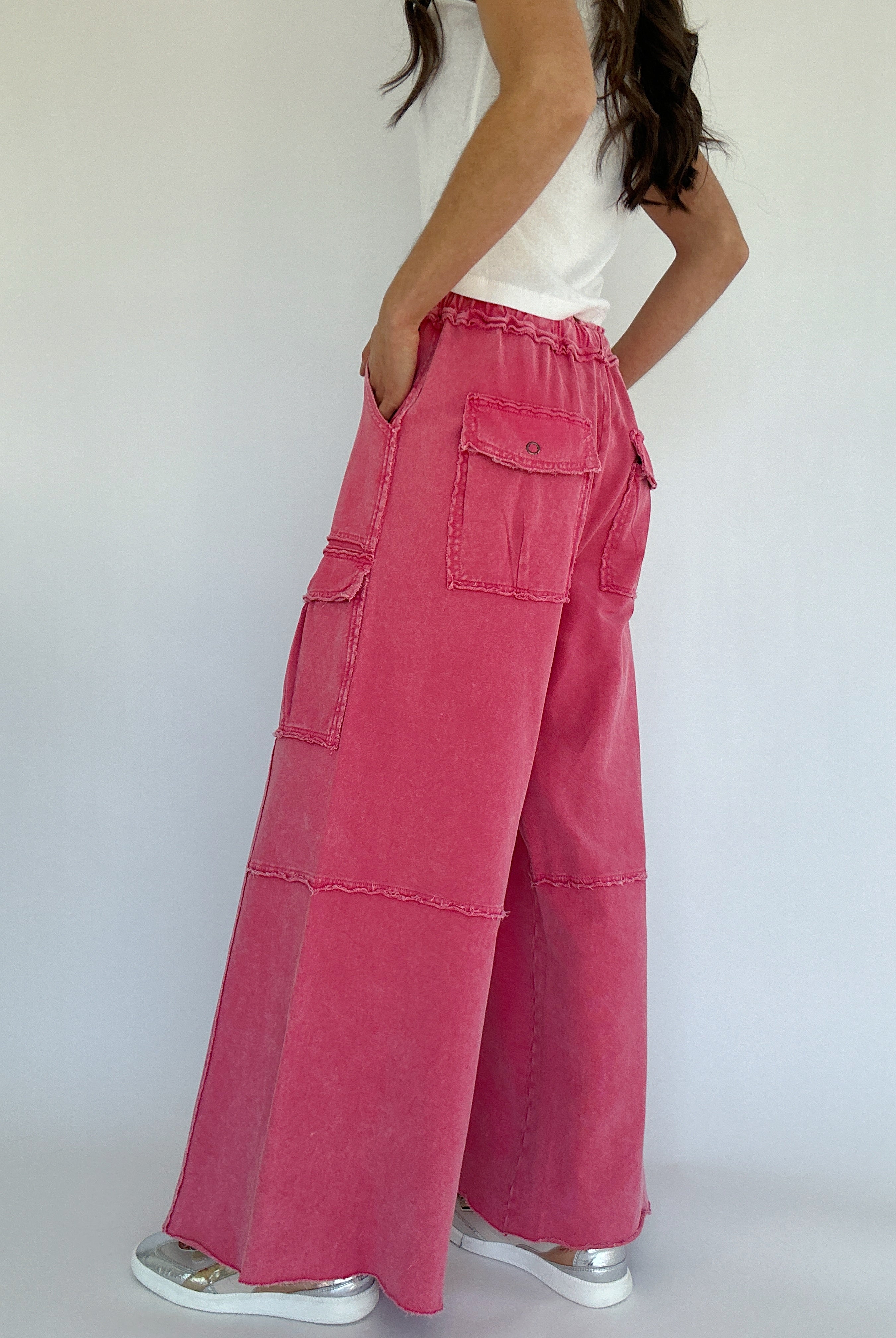 Person wearing pink wide-leg pants with a white top against a plain background