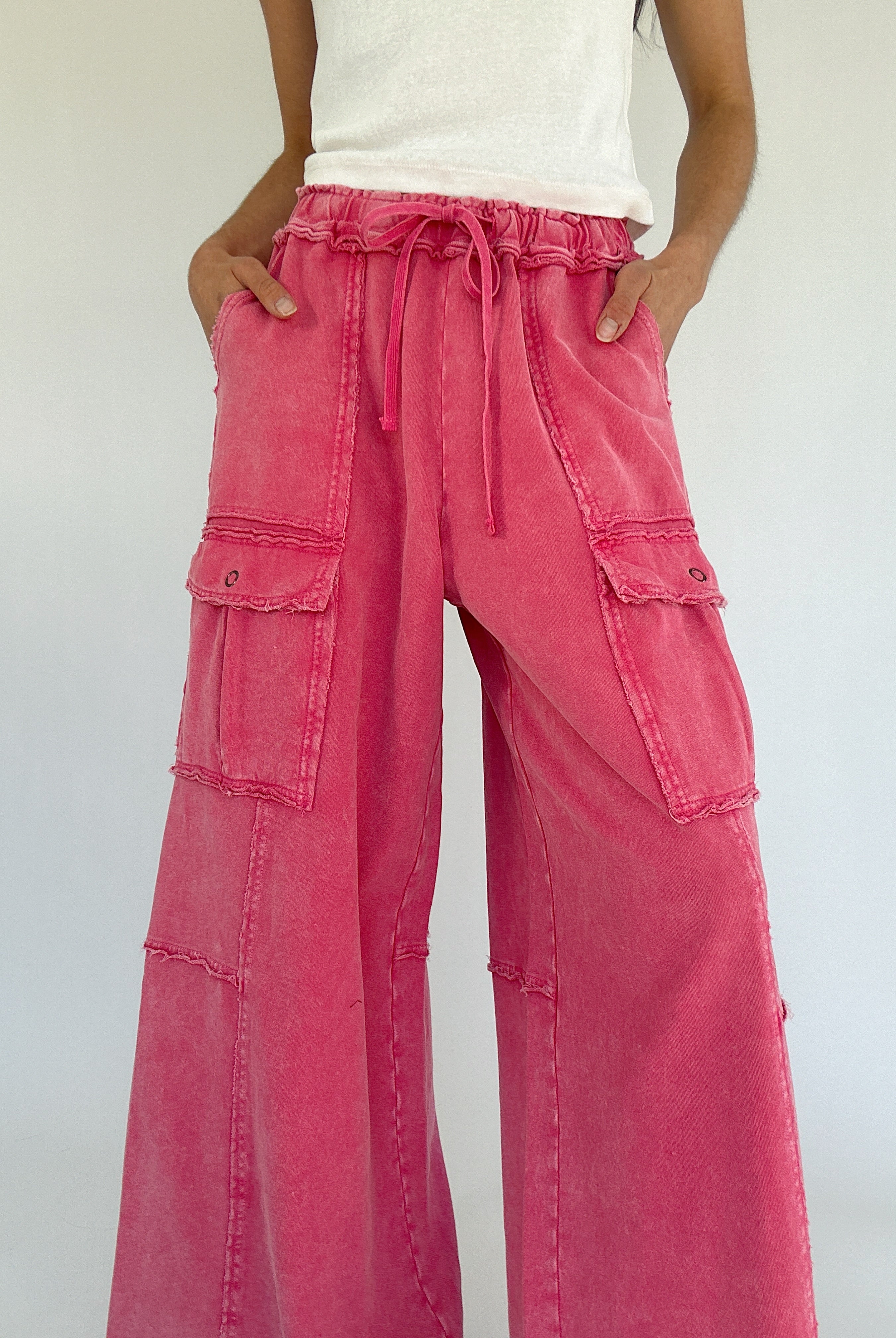Person wearing bright pink cargo pants with a white background showing drawstring waist and side pockets