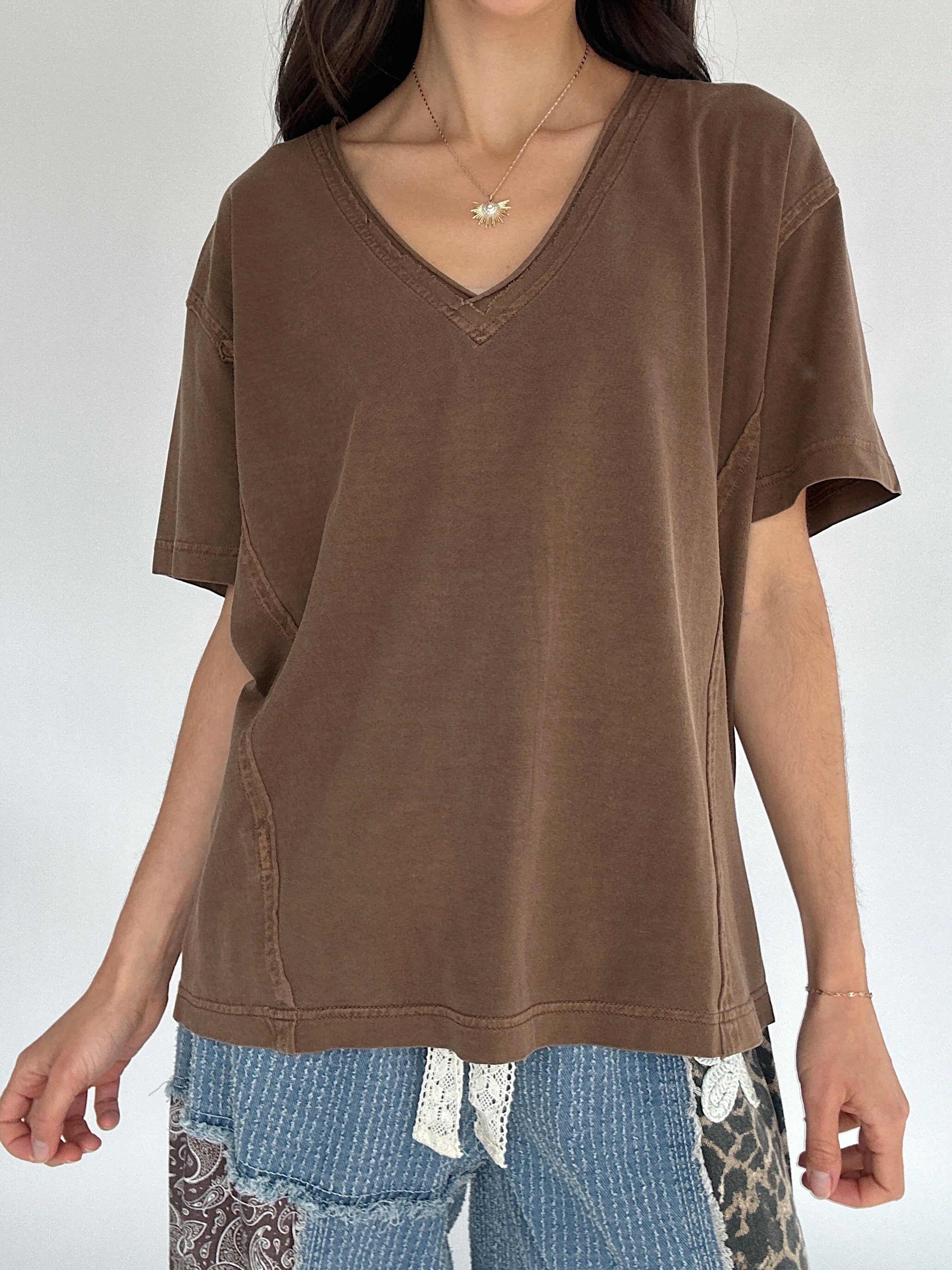 Person wearing a brown V-neck t-shirt with a plain background