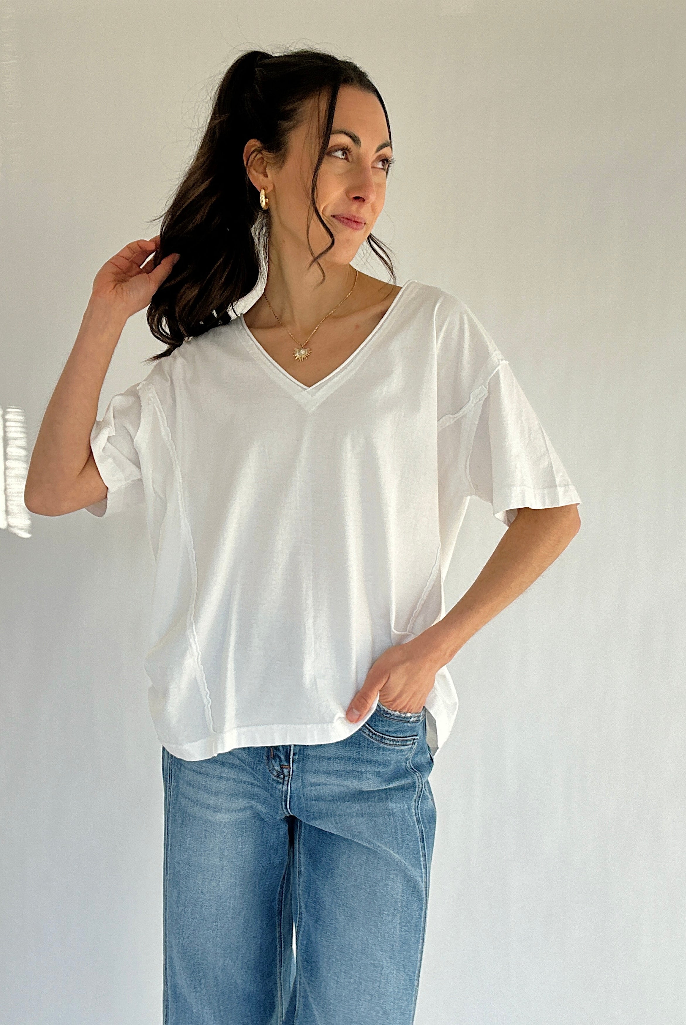 Woman wearing a white t-shirt and blue jeans against a plain background