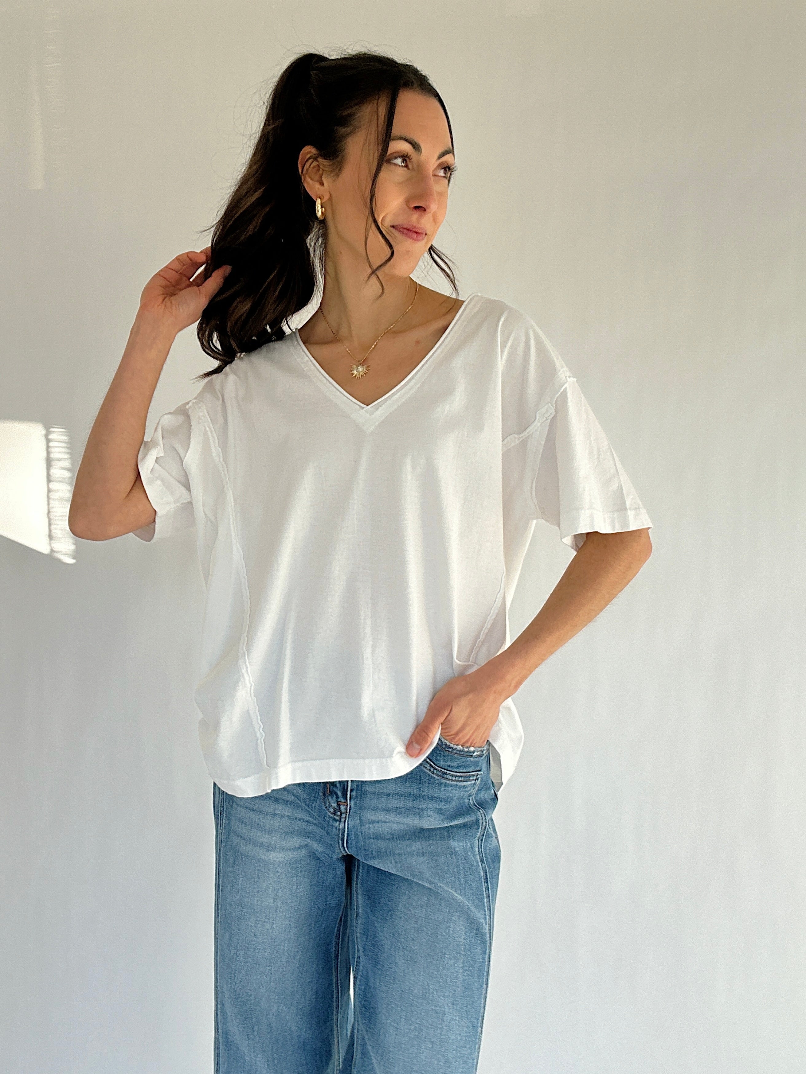 Woman wearing a white t-shirt and blue jeans against a plain background