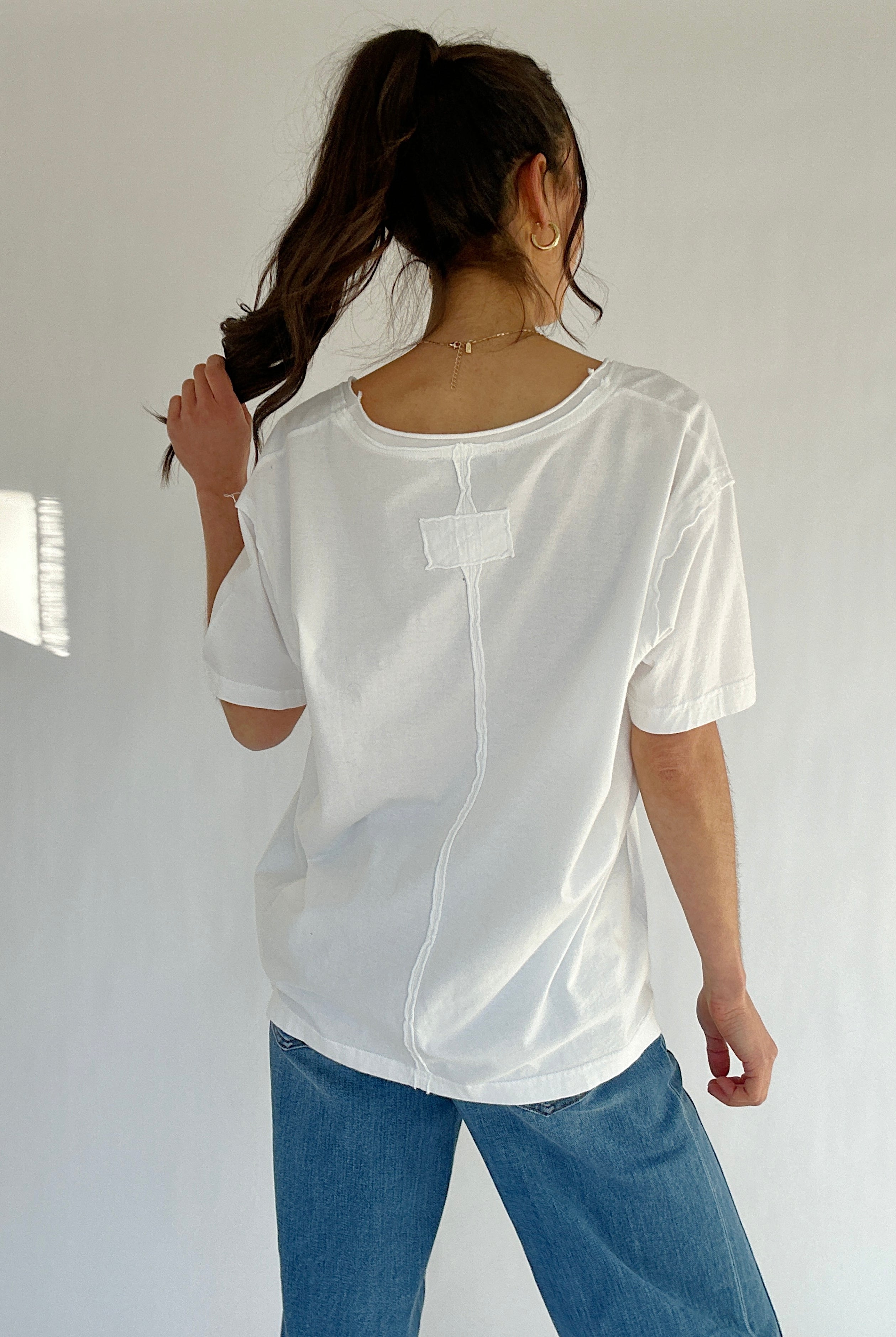 Person wearing a white shirt and blue jeans against a plain background