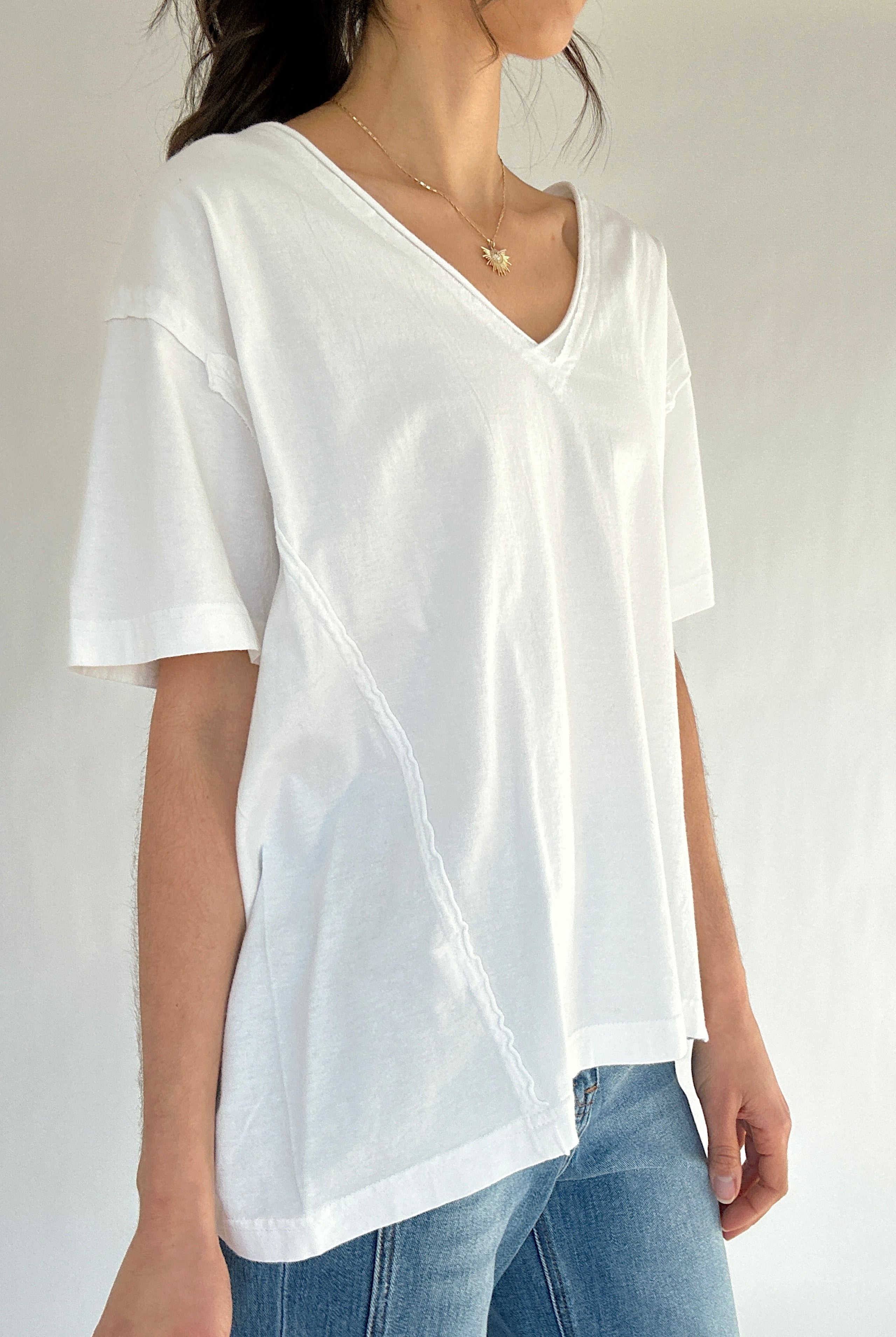 Person wearing a white t-shirt and blue jeans against a plain background