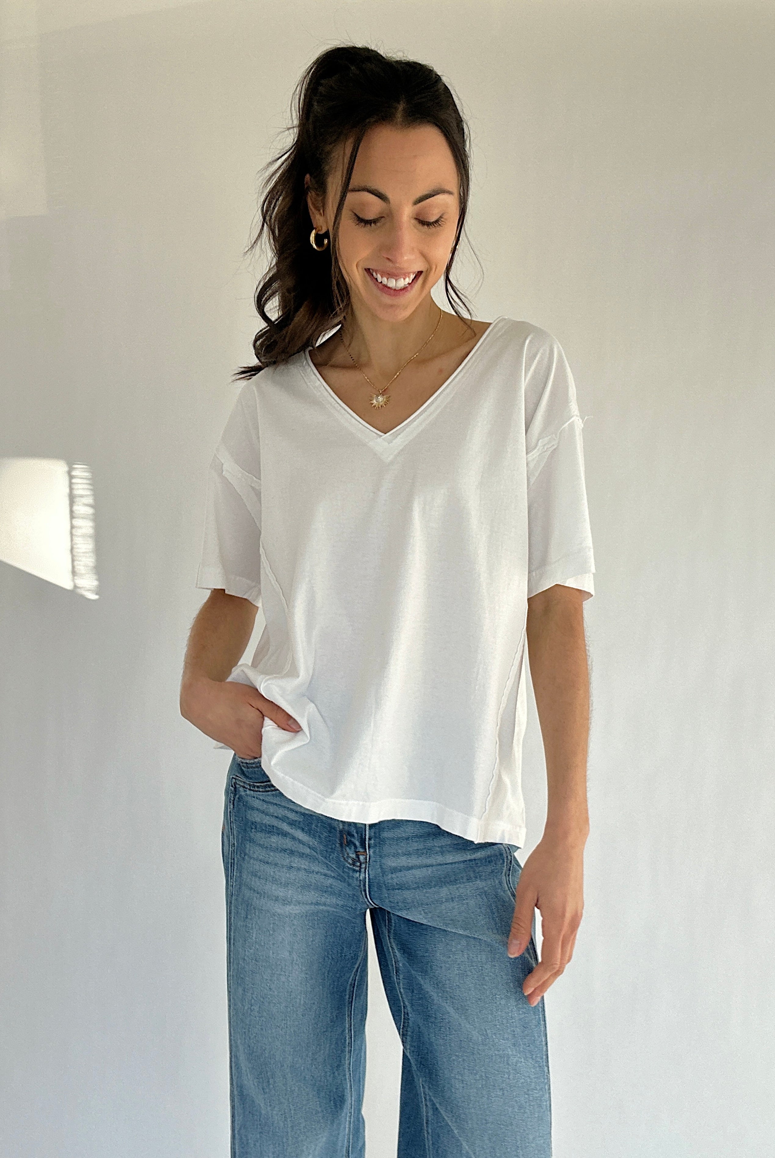 Woman wearing a white t-shirt and blue jeans against a plain background